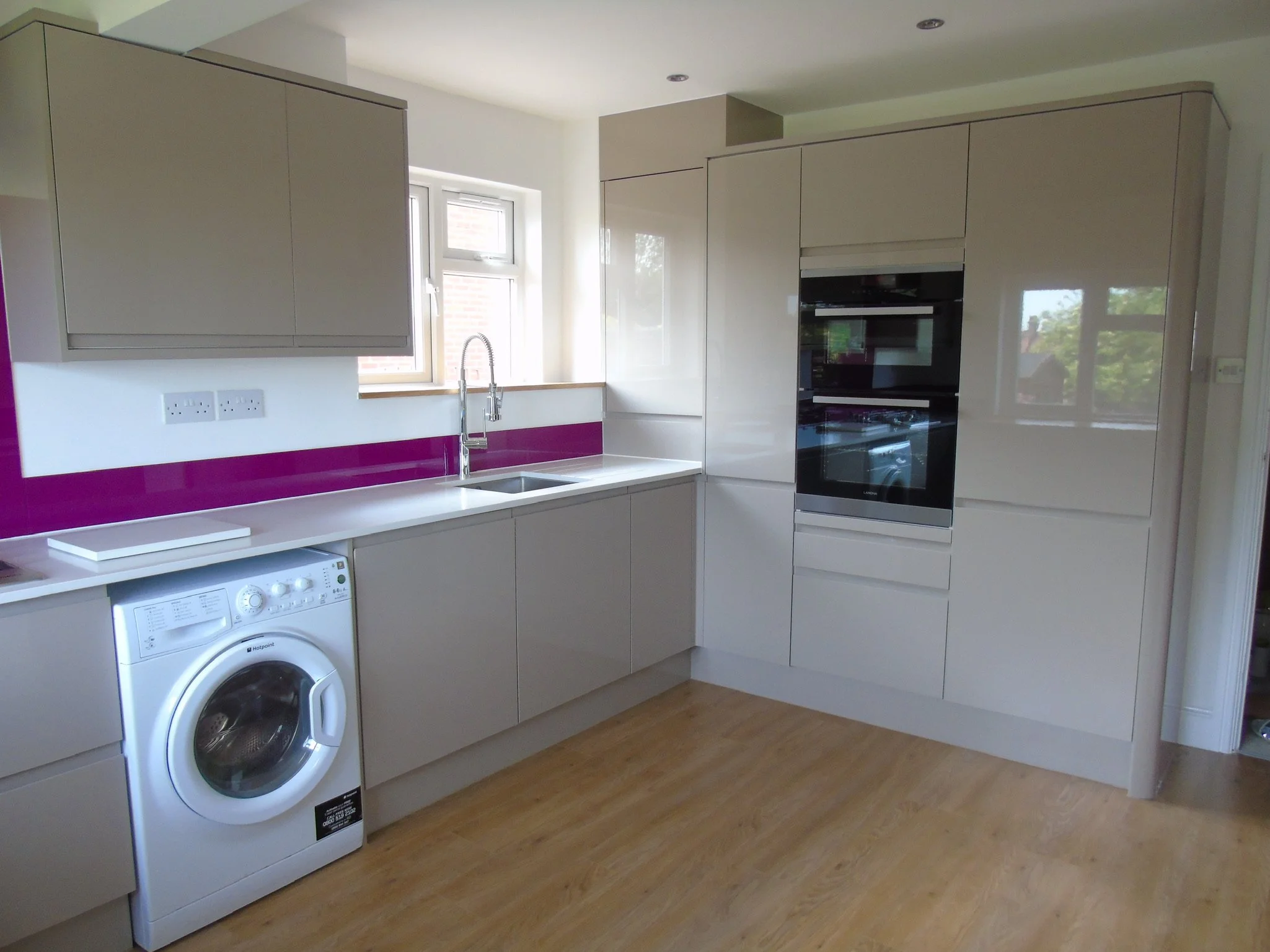 Stone gloss integrated handles, quartz and solid oak worktops, coloured glass upstands