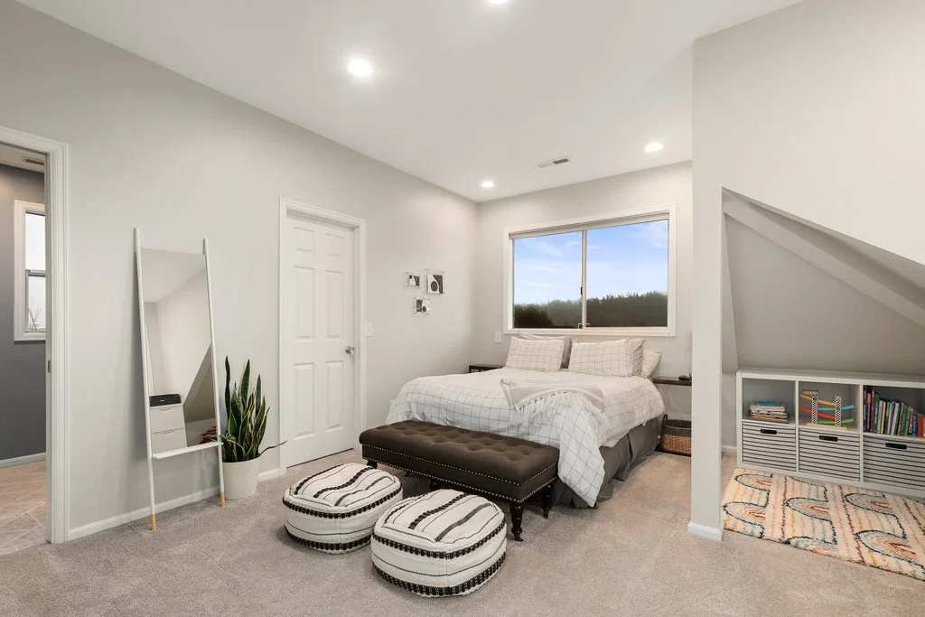 A modern bedroom with a bed, window, mirror, plant, and storage shelves.