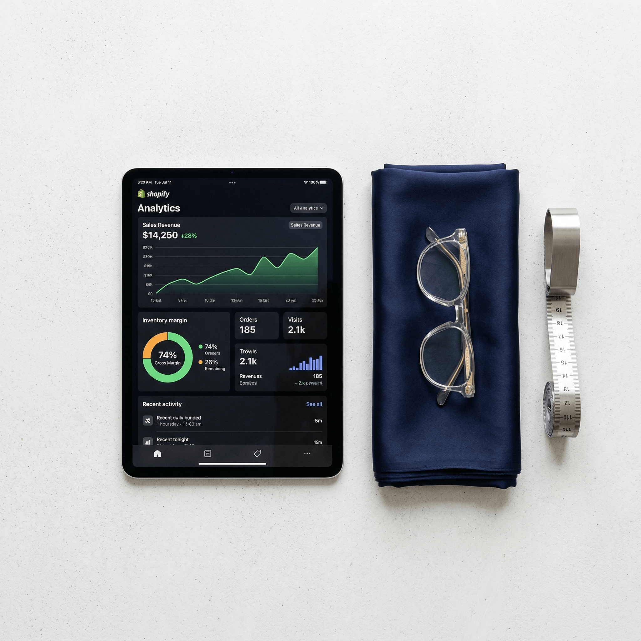 Minimalist flat-lay showing a Shopify dashboard alongside folded silk fabric, visualizing financial visibility for fashion brands.