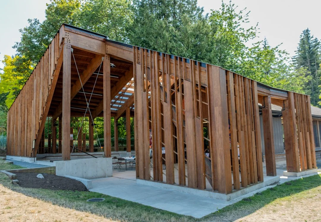 Totest Aleng: Indigenous Learning House in Surrey, BC with cedar framing and concrete foundation, surrounded by green trees.