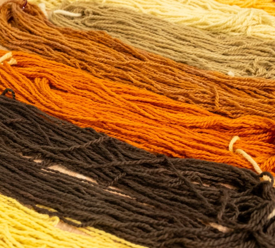 Close-up of colorful yarn strands in shades of yellow, orange, brown, and beige.