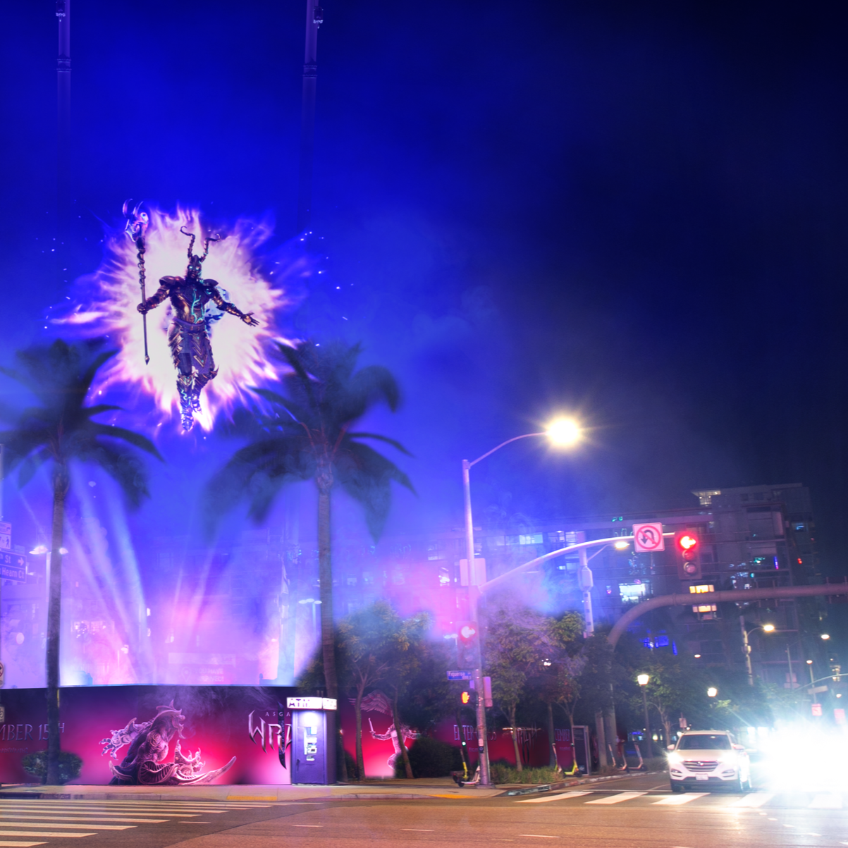 Nighttime city street with illuminated large sign of a flying figure with a staff, surrounded by purple and blue lights, palm trees, streetlights, cars, and traffic signals.