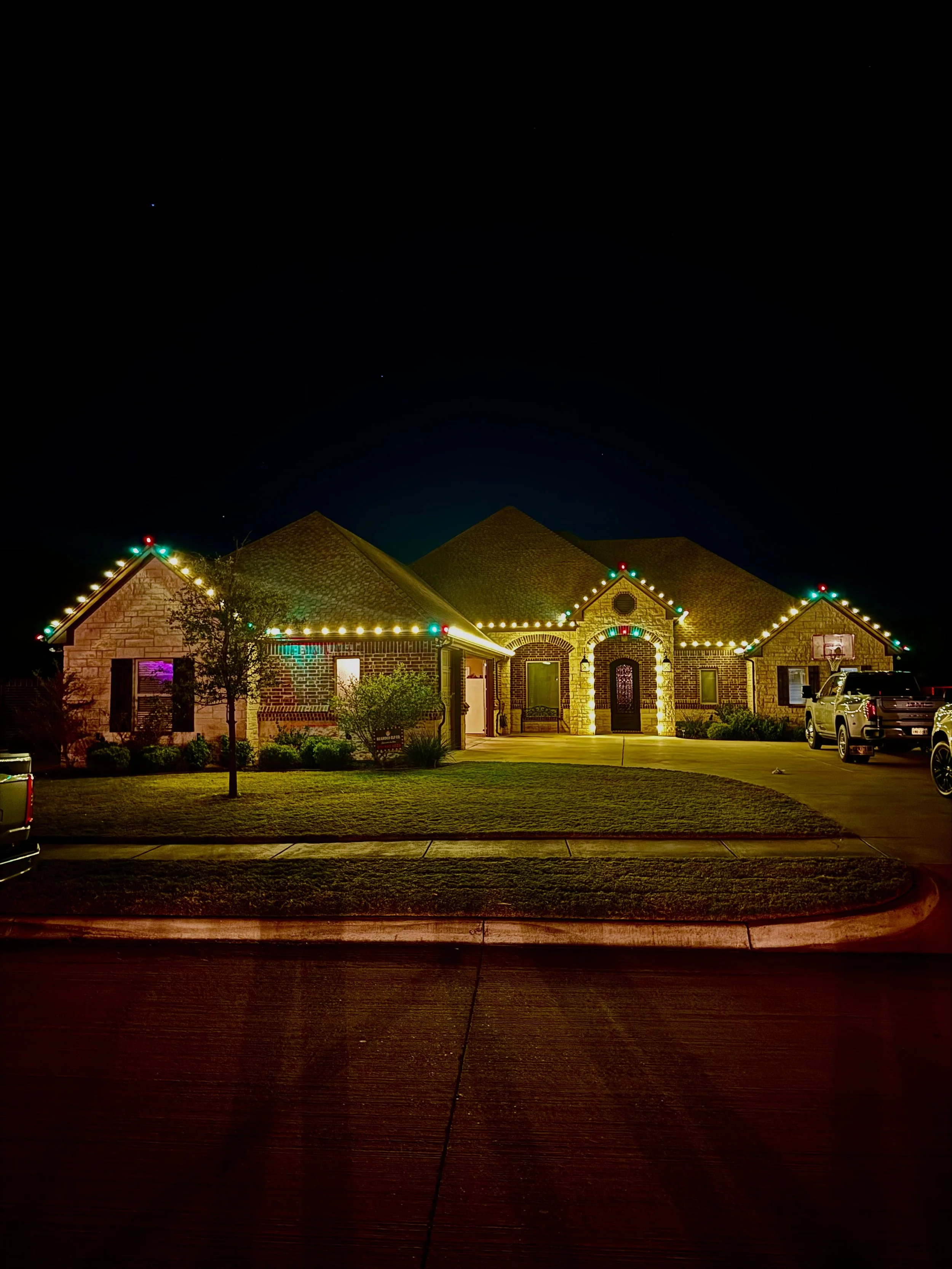 Residential Christmas light installation in Pecan Plantation Texas. Red, green and warm white roofline lighting and entrance lighting by Bearded Elf Co.