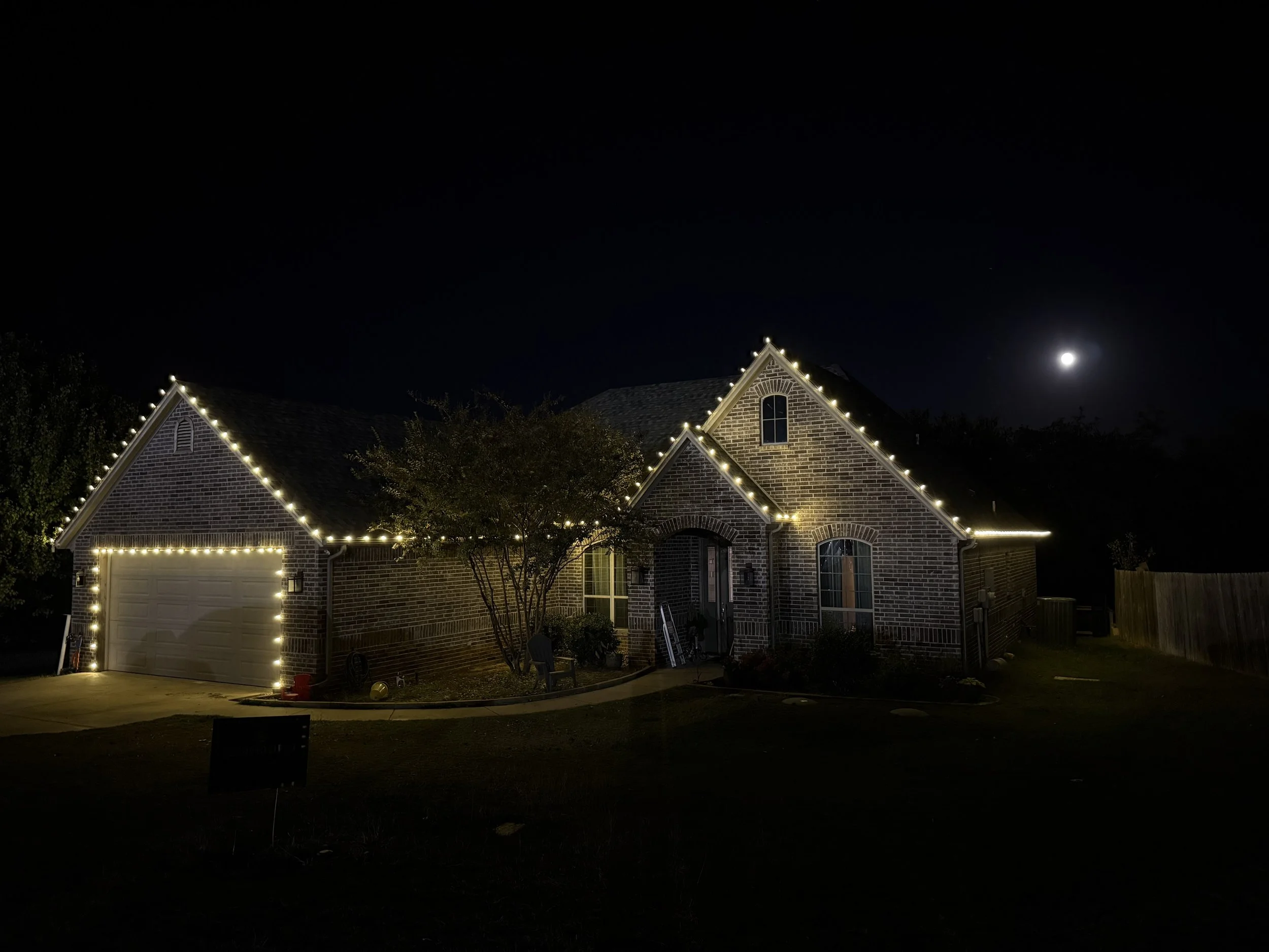 Residential Christmas light installation in Granbury Texas. Warm white roofline and garage lighting by Bearded Elf Co.