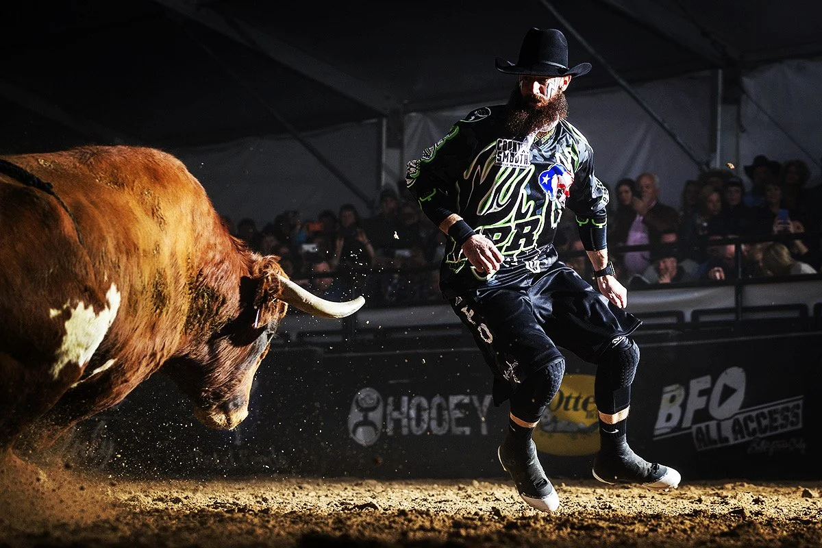 Weston Rutkowski professional freestyle bullfighter facing charging bull at BFO Bullfighters Only event — Bearded Elf Co. founder Granbury Texas