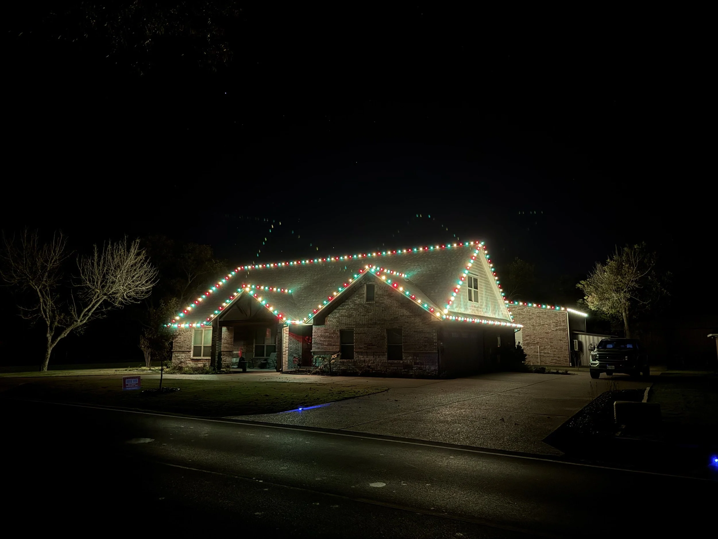 Residential Christmas light installation in Granbury Texas. Red, green and warm white roofline lighting by Bearded Elf Co.
