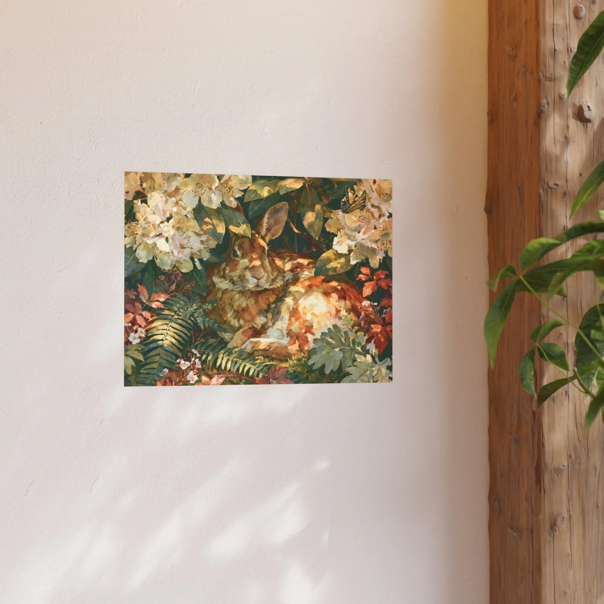 Rabbit in the Rhododendron 24 x 18 art print displayed on a light wall beside a wood shelf and green plant