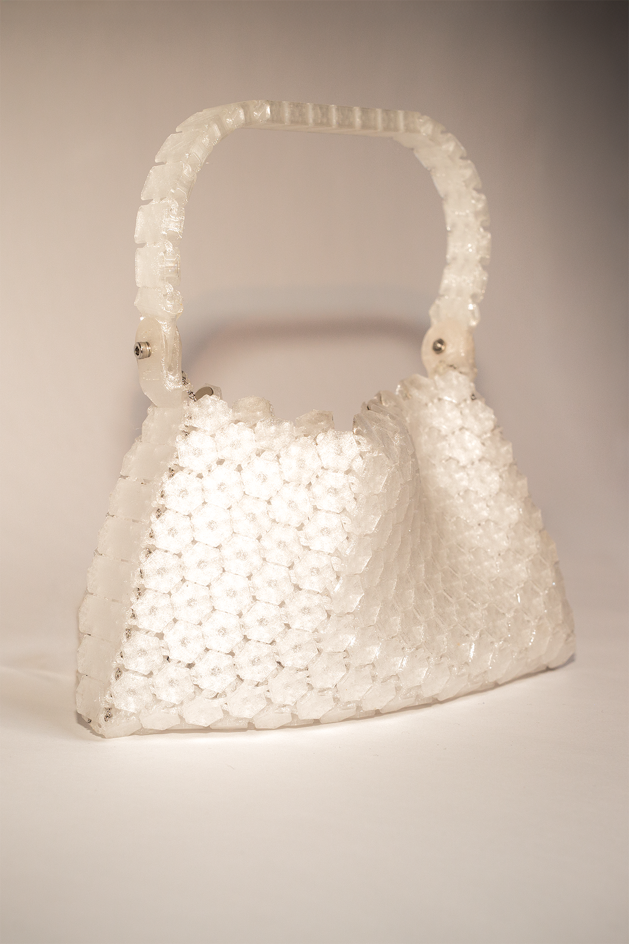 A handbag-shaped sculpture made of clear, textured plastic honeycomb panels with a handle.