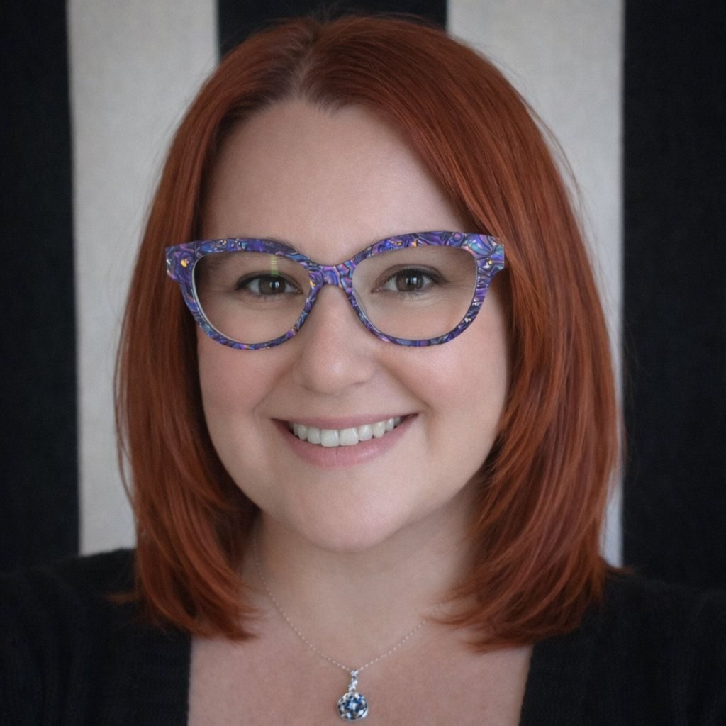 woman in purple glasses with dark red hair smiling
