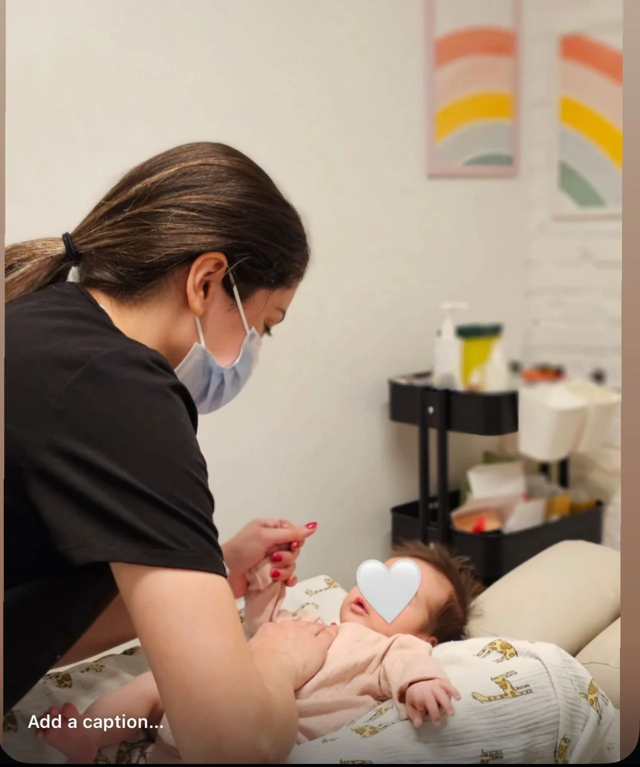 A woman wearing a face mask is attending to a child lying on a hospital bed, holding the child's hand in a medical setting.