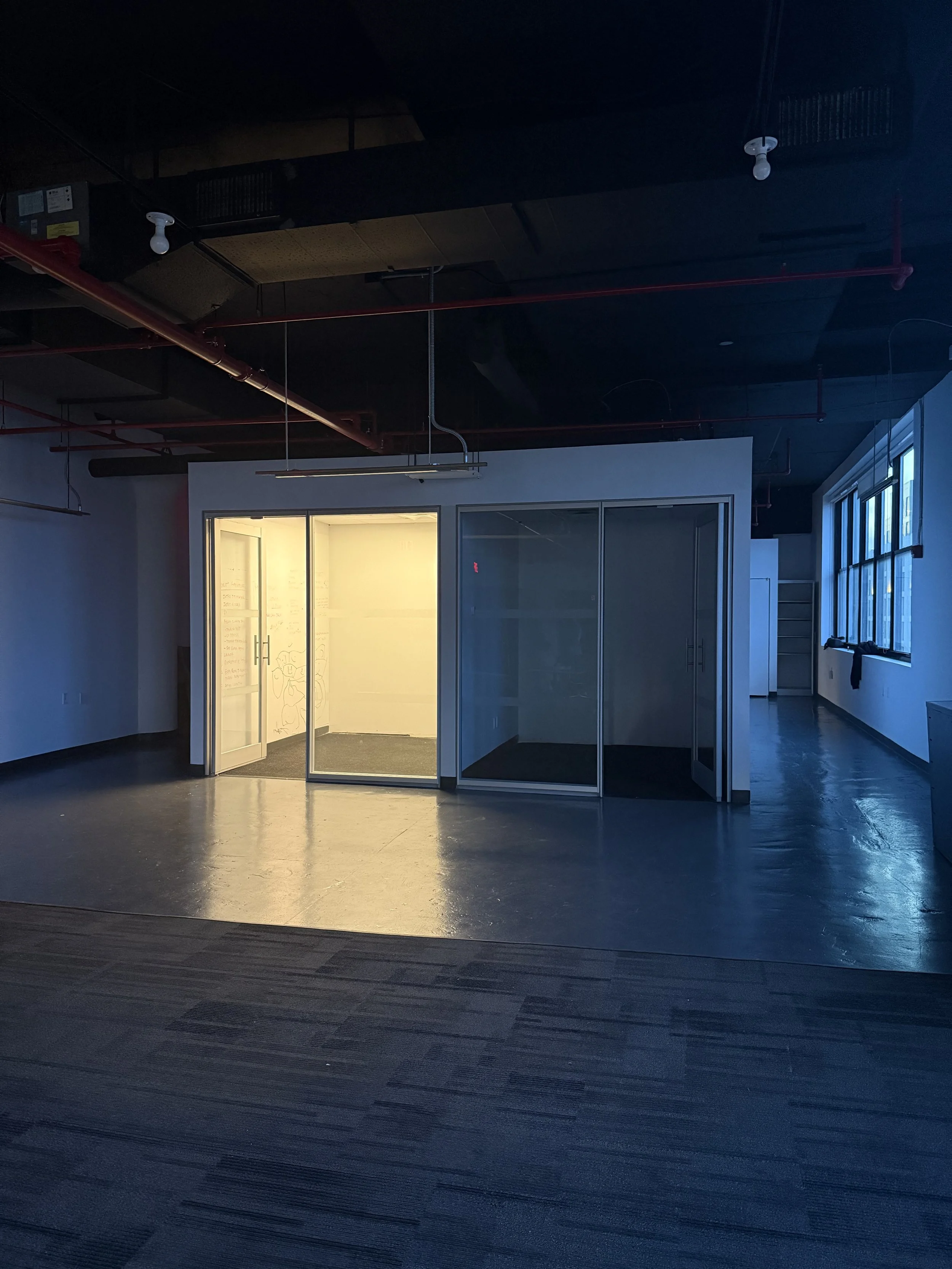 Exhibition space by The Gallery in Brooklyn, featuring an open-plan layout with glass partitions and industrial ceiling