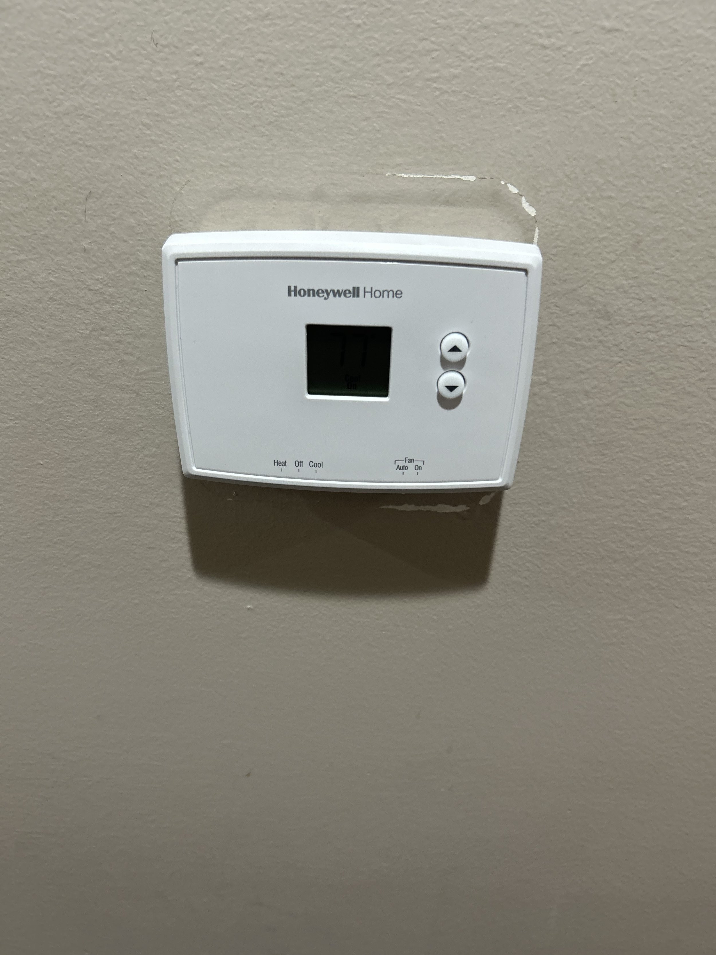 White Honeywell Home thermostat mounted on a beige wall.