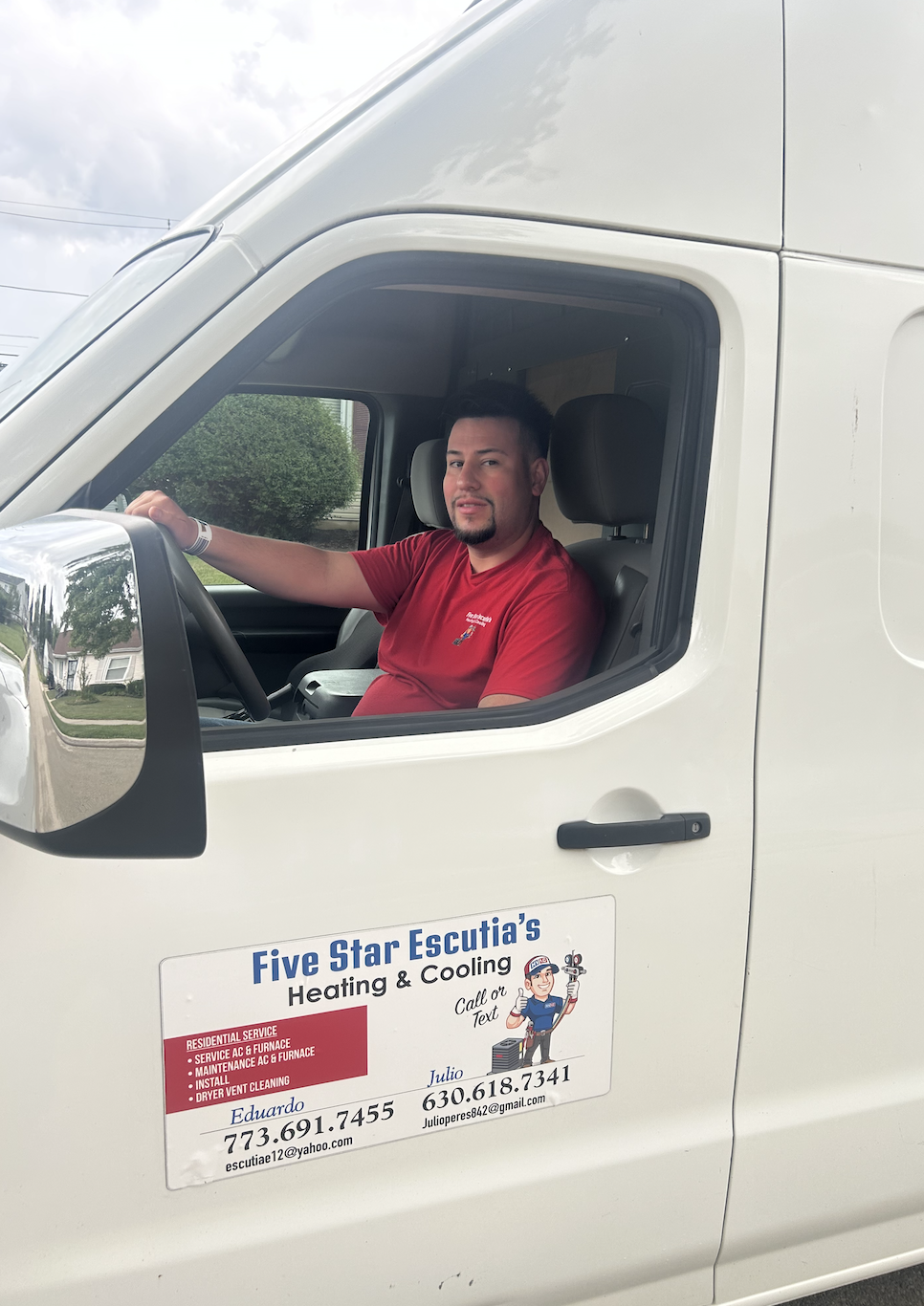 A man sitting in the driver's seat of a white service van with the company logo and contact information on the door.