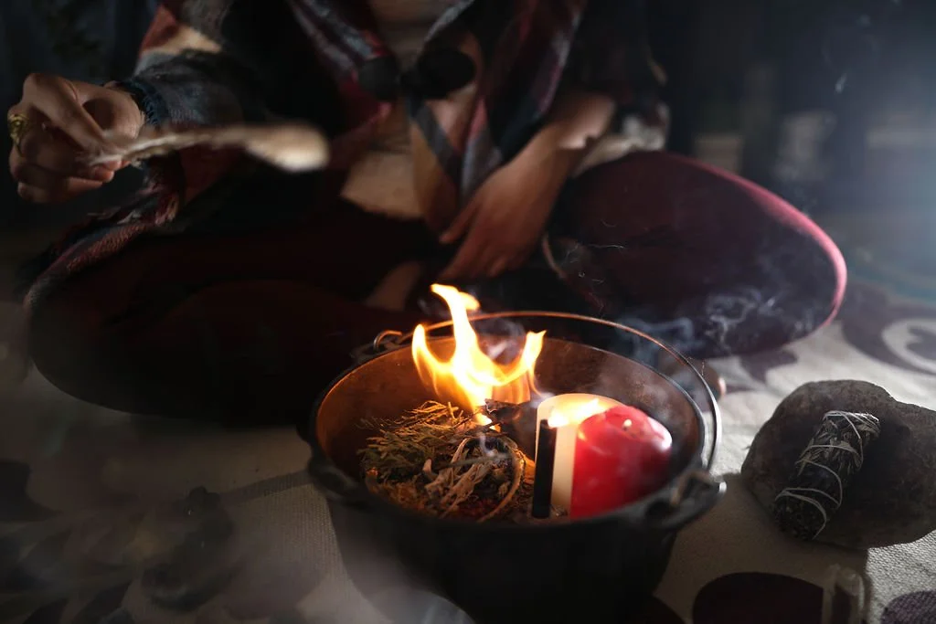 Sacred Fire moon ritual in a cast iron cauldron with red, black and white candles, a feather and sage