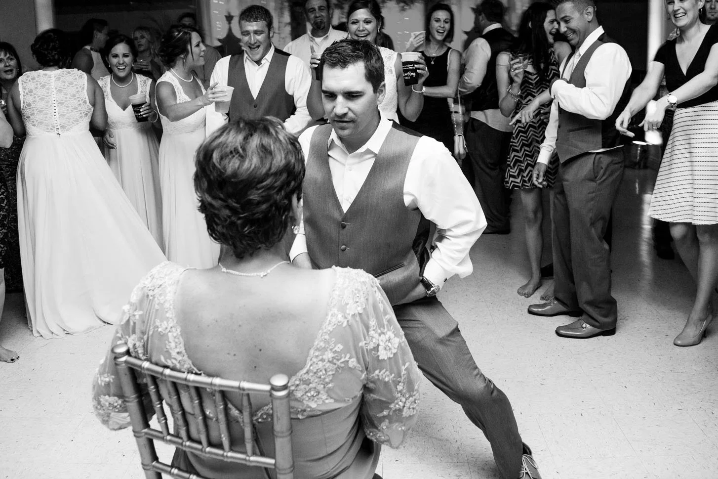 A man dances in front of a seated woman at a lively reception, adding to the night’s collection of strange wedding day stories.