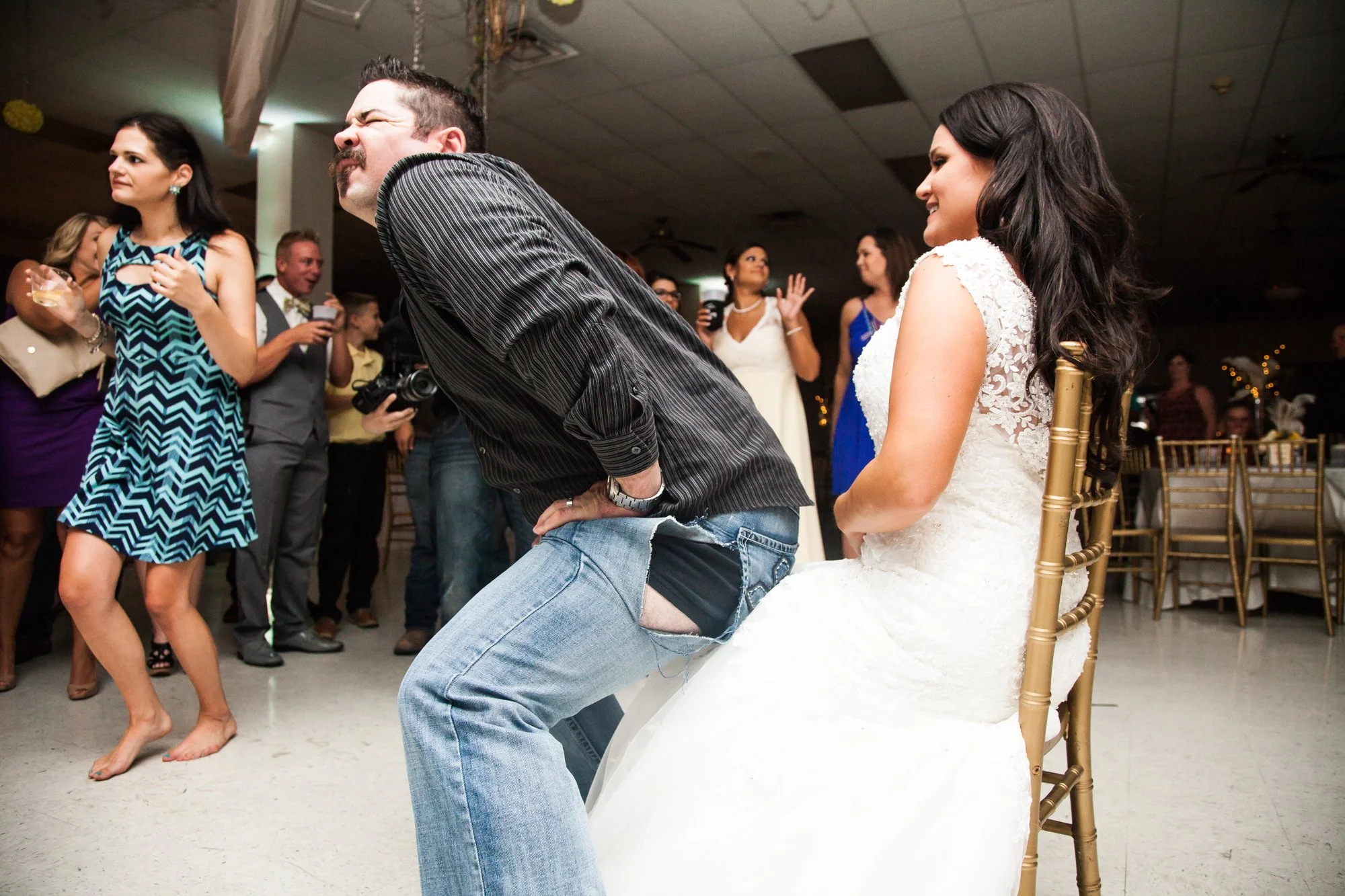 A man with ripped jeans dances humorously for the bride, adding to the strange wedding day stories at a lively reception.