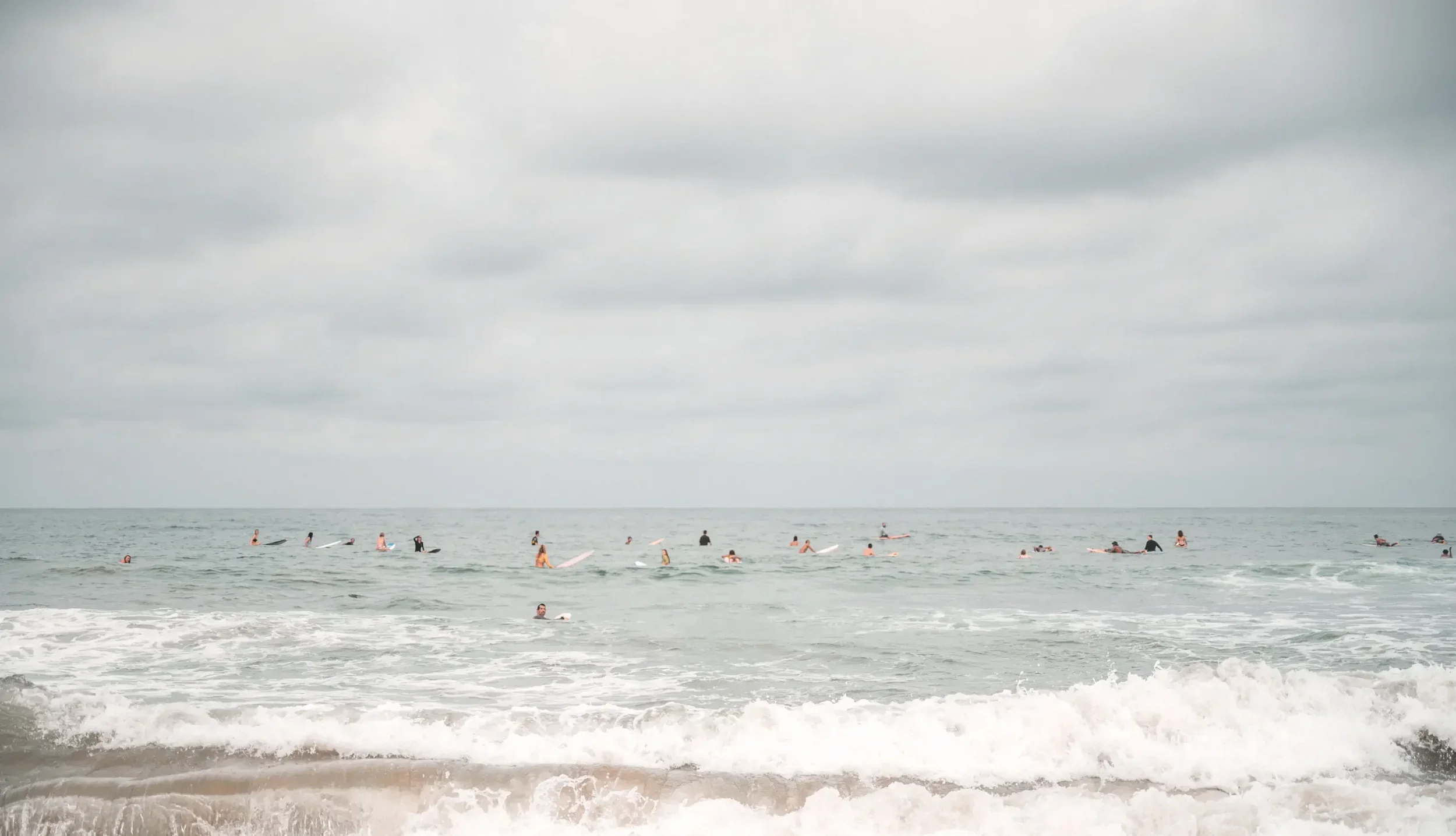 Surfers in the ocean at Sayulita's main beach on a cloudy day
