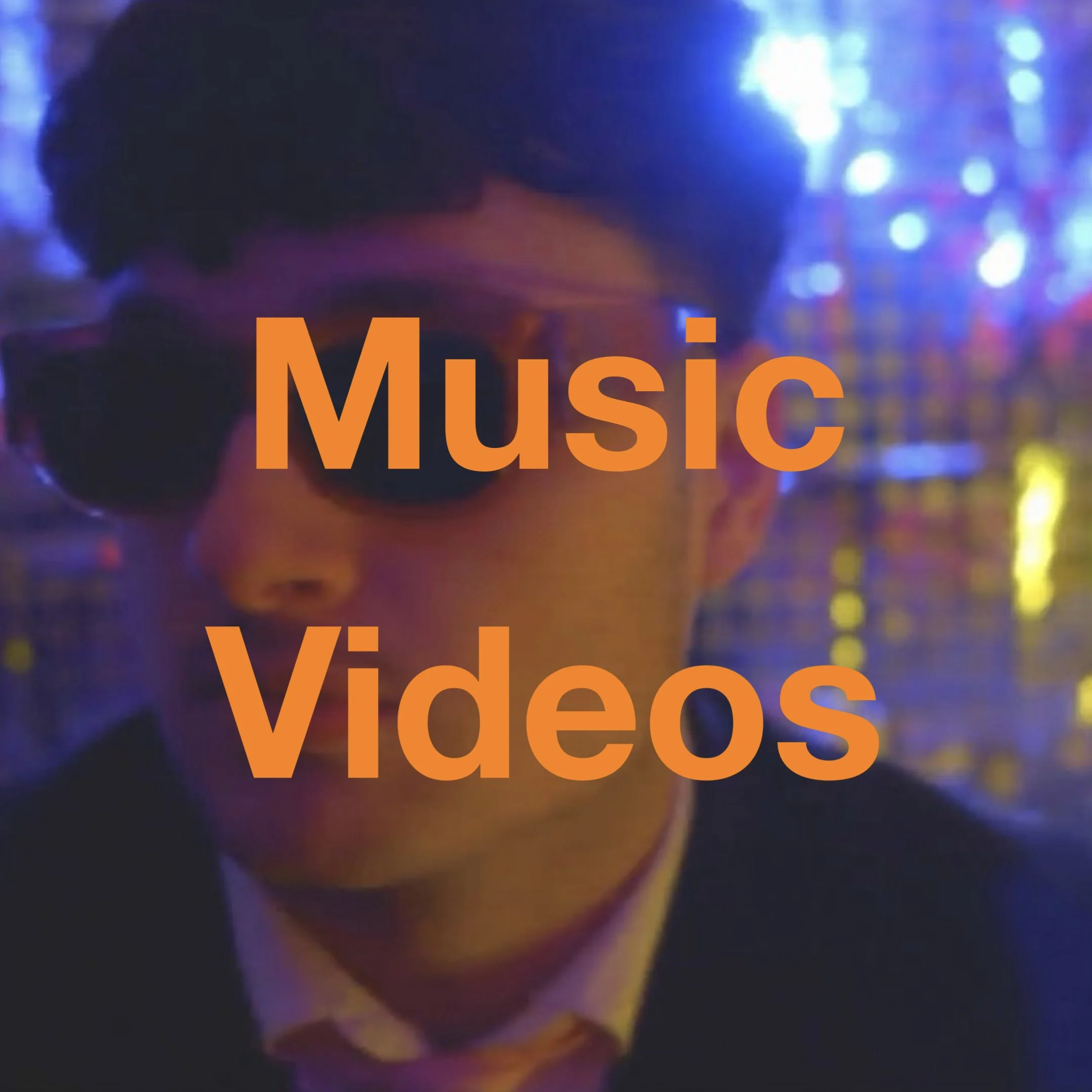 A person with dark hair in a dimly lit environment with colorful lights, with the word 'Music' in large orange letters at the bottom.