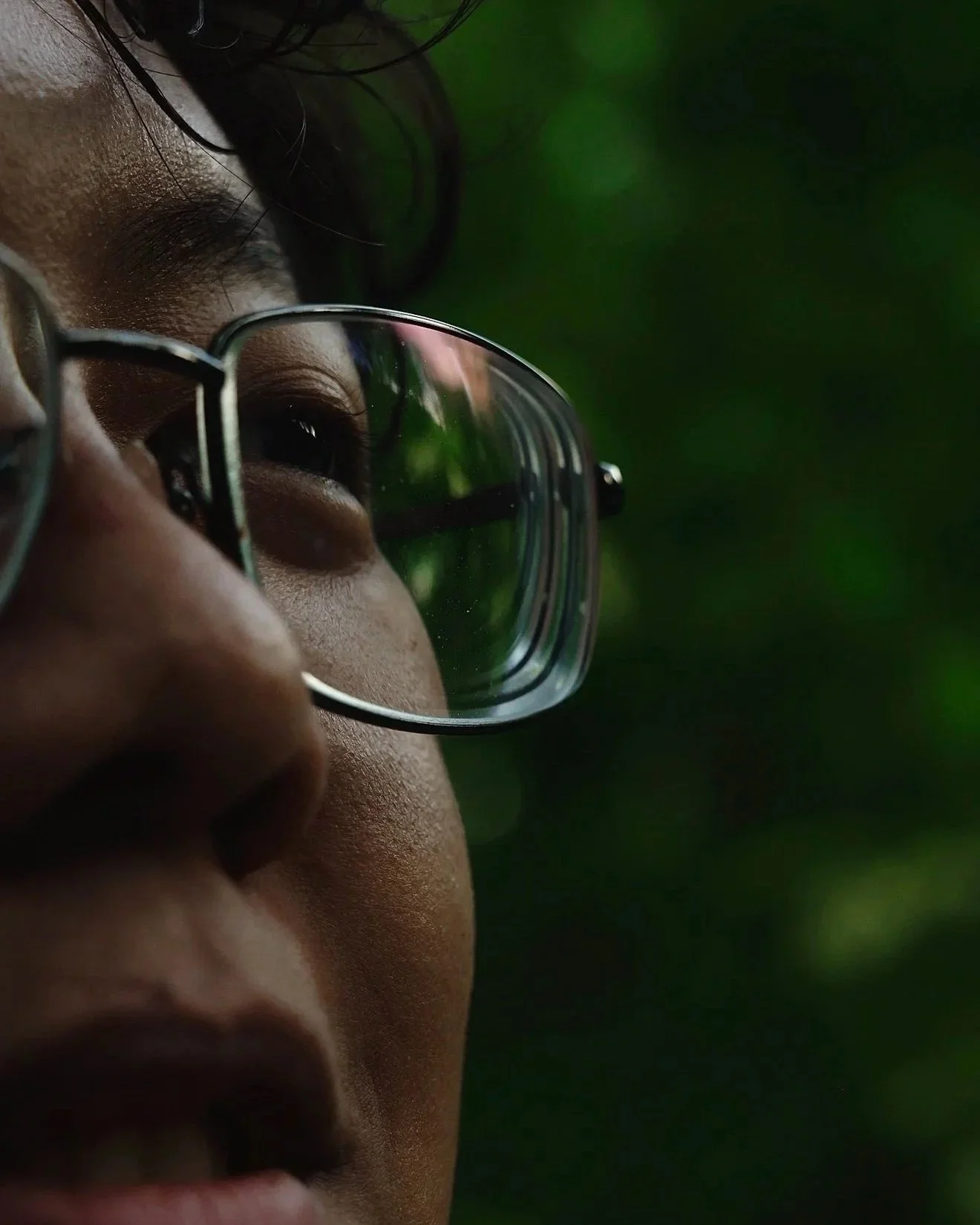 Close-up of a child's face wearing glasses with a green blurred background.