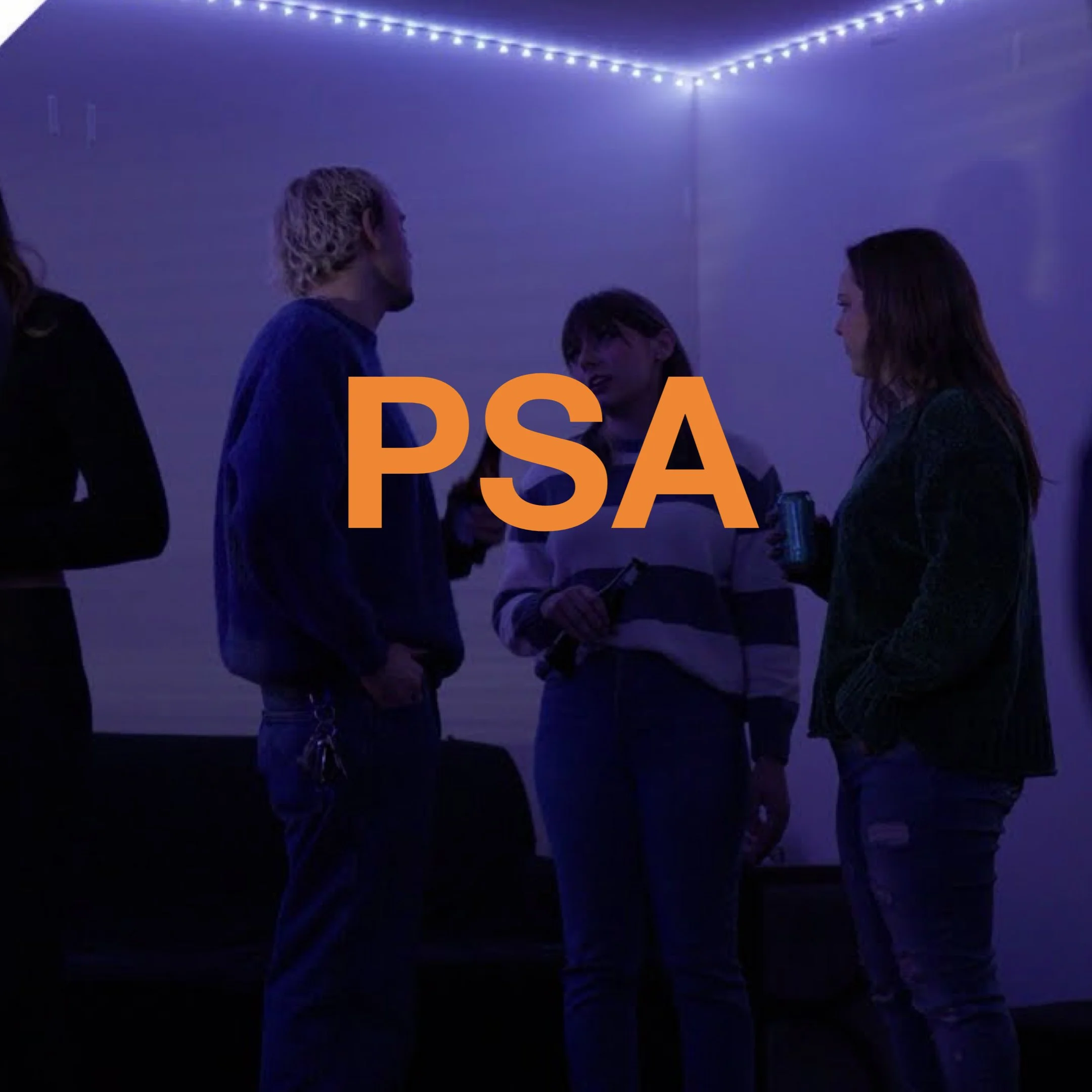 Group of people having a conversation at a gathering in a dimly lit room decorated with string lights.
