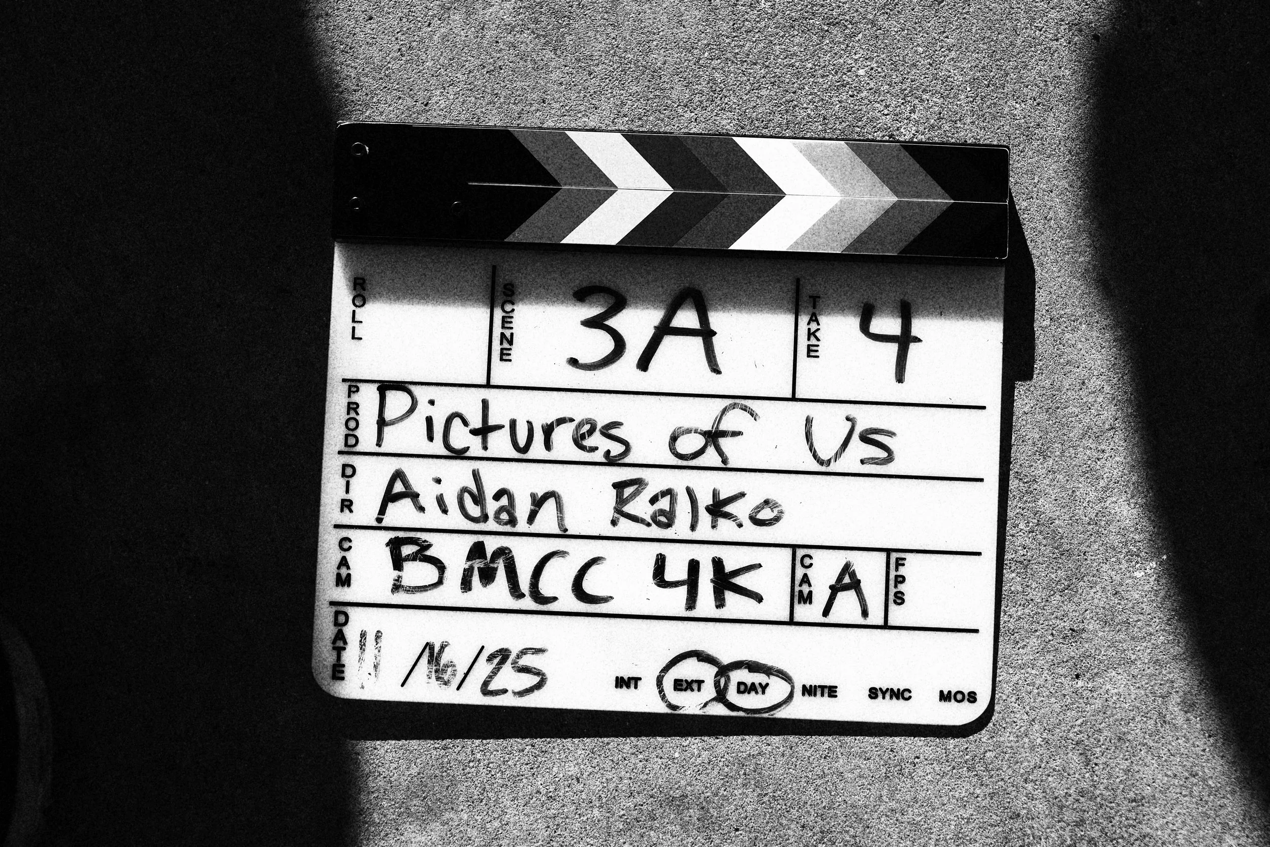 Black and white film clapperboard on a textured surface with handwritten notes.