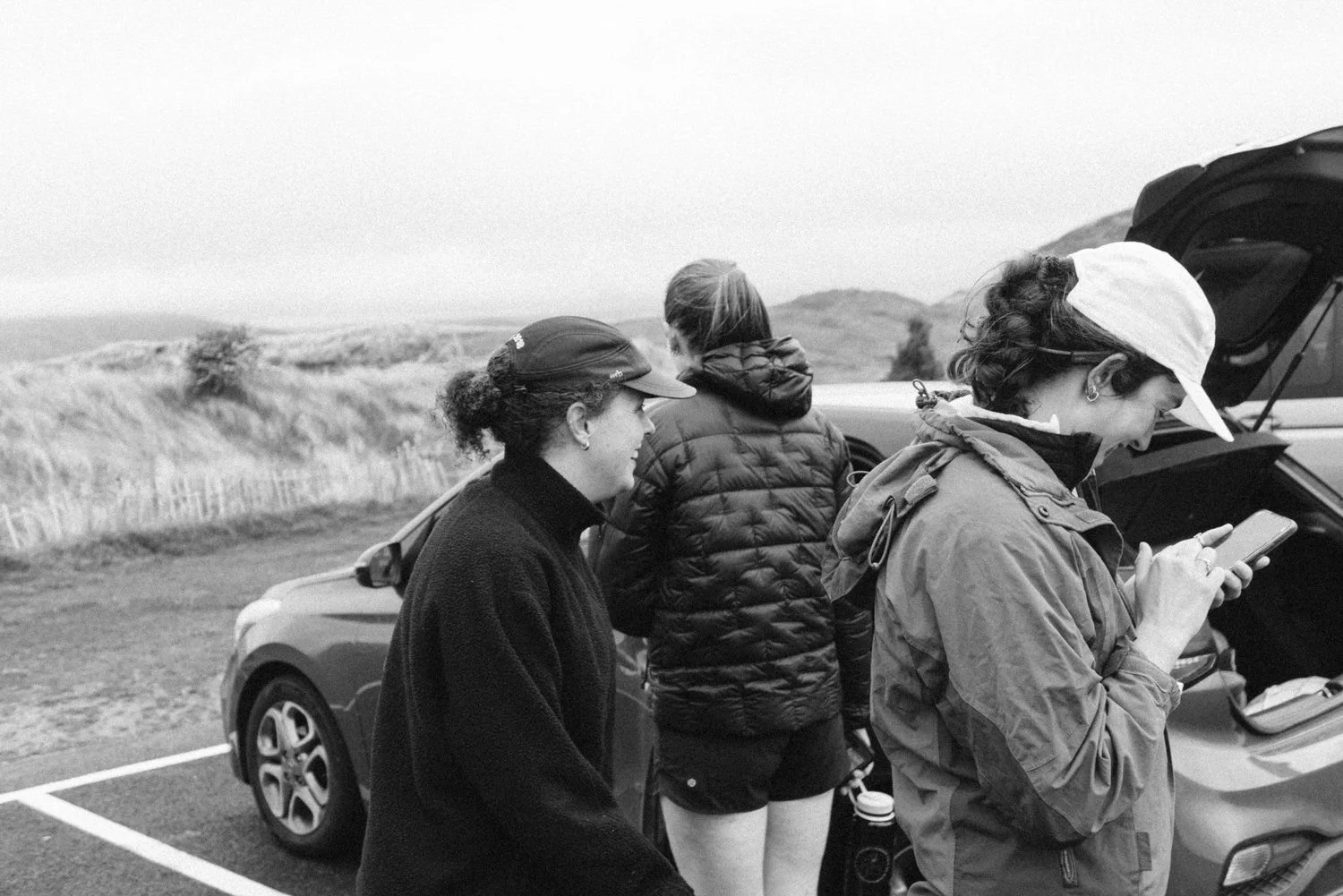 Four people at the open boot of a car, sorting kit at the roadside
