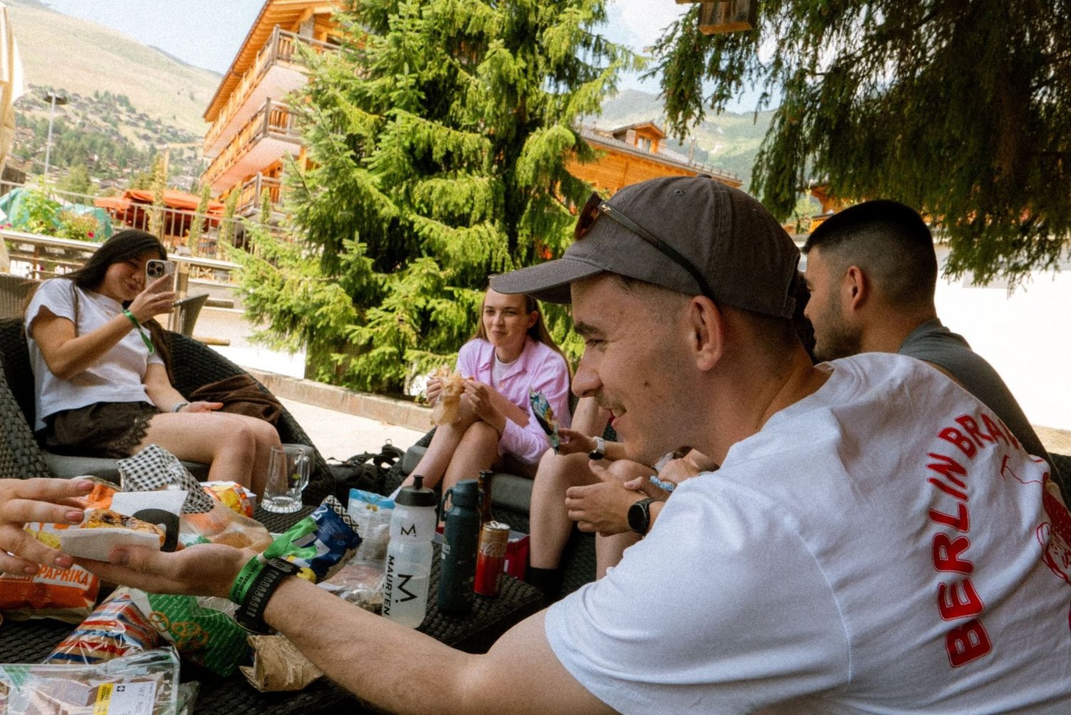 People sitting outside eating together, food and bottles spread around them