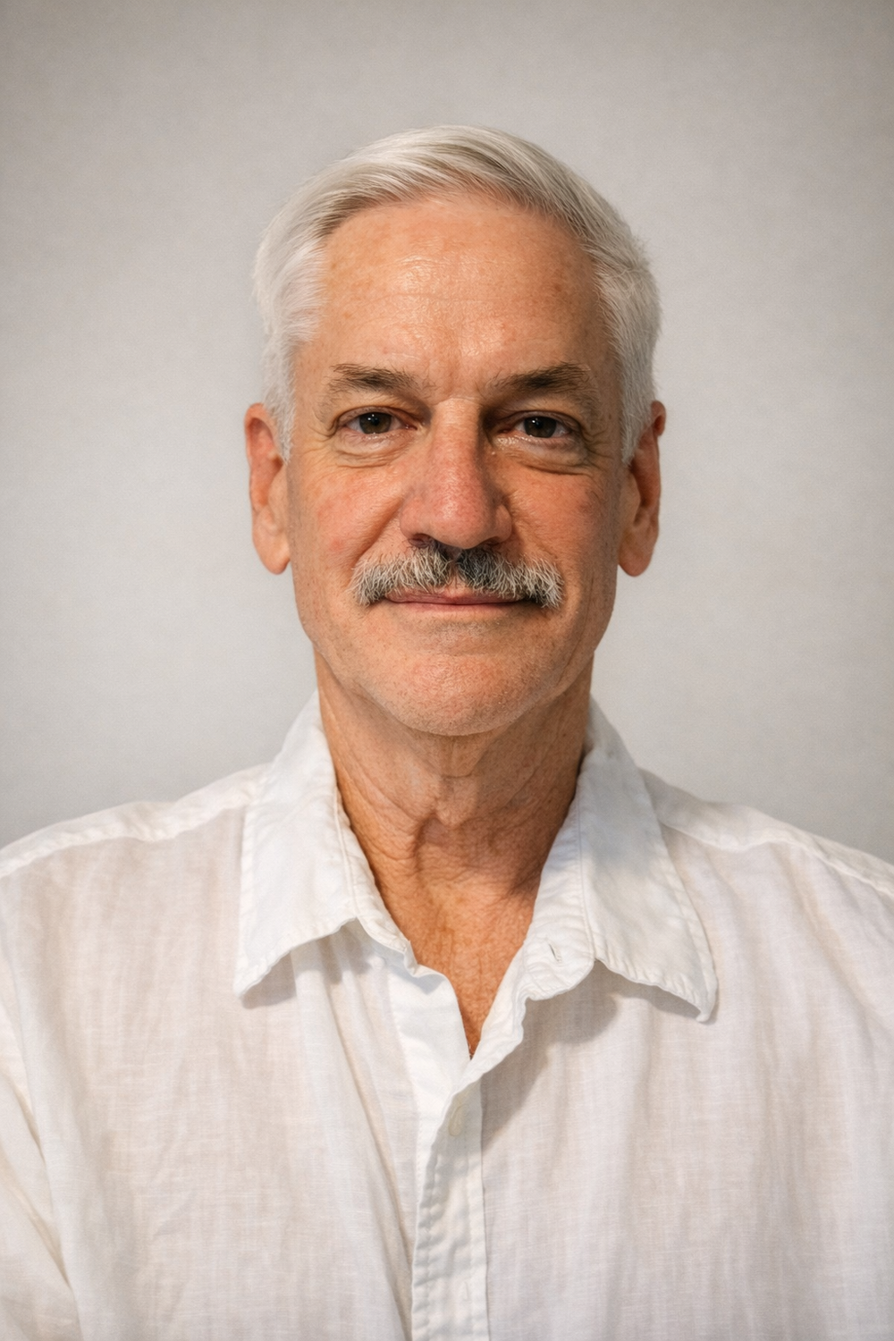 Warwick Howlett, in a white shirt against a plain grey background