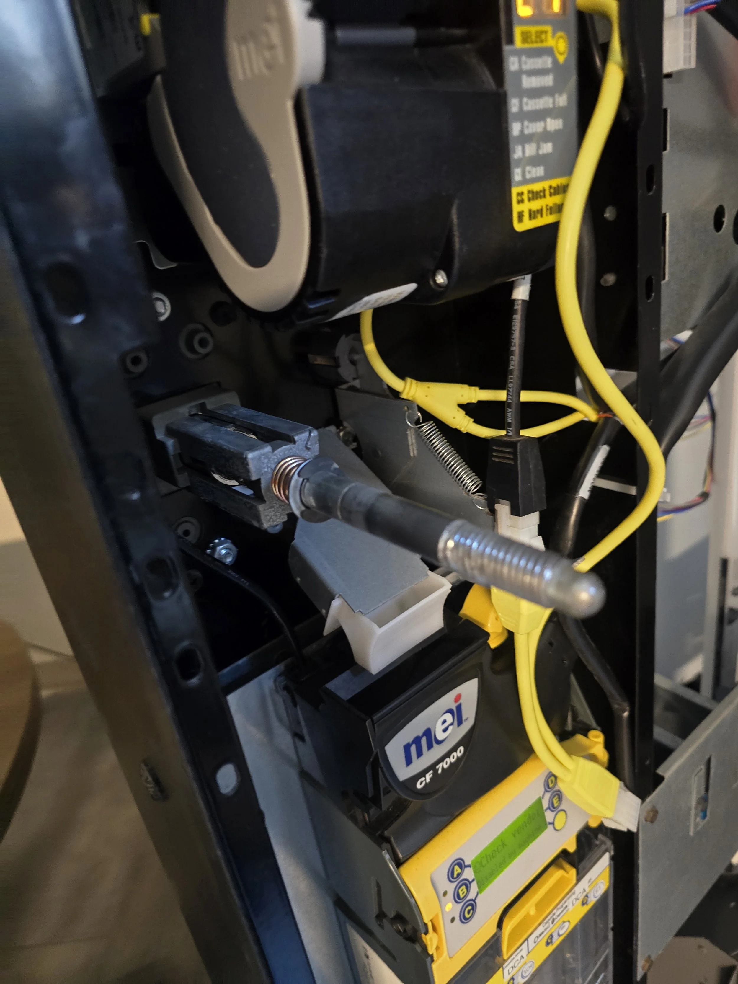 Close-up of an industrial machine with yellow electrical wires, a black component, and a label indicating it is a Metzger Generator model GF 7000.