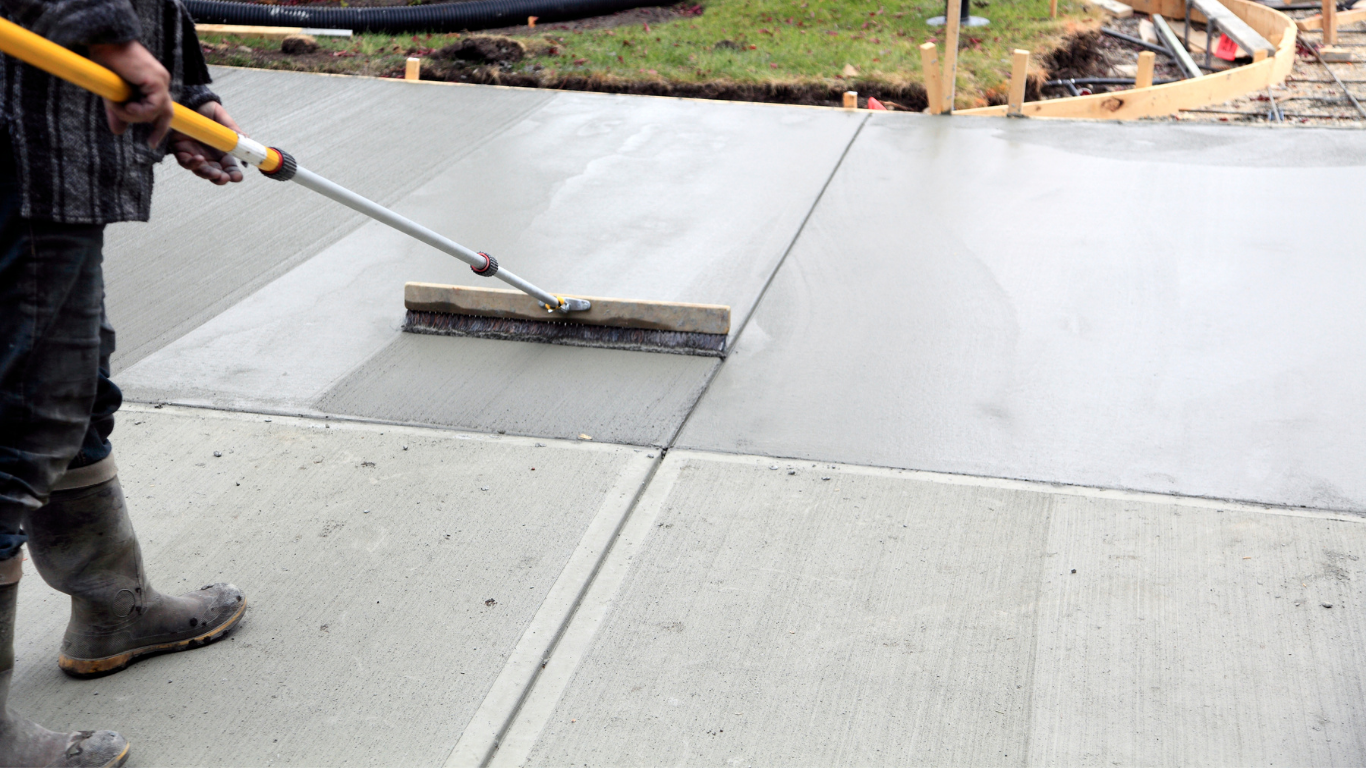 Concrete driveway installation by Concrete Concepts & Exteriors featuring professional craftsmanship with a crew member smoothing freshly poured concrete for a durable, long-lasting finish