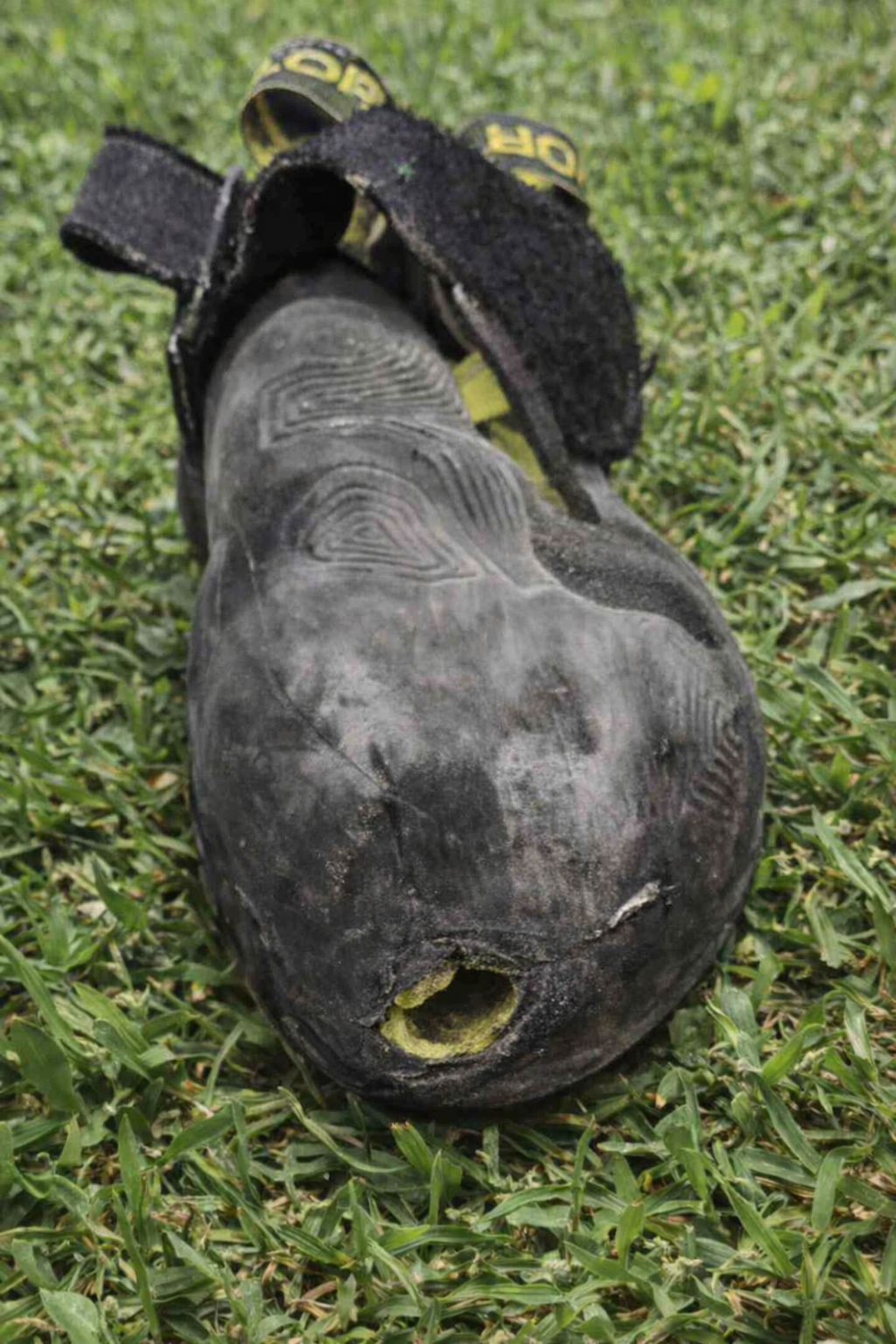 A black and yellow weighted vest shaped like a bomb with a faux fuse on the front, lying on green grass outdoors.