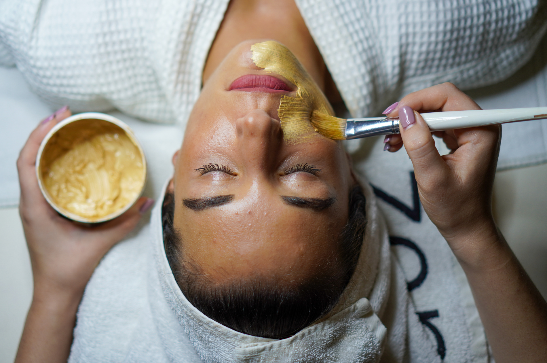 Client receiving a professional skin treatment with a treatment mask application.