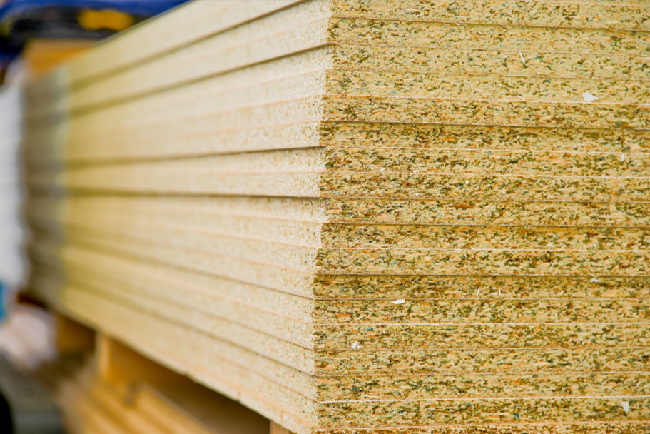 Modern kitchen with beige cabinets, marble countertops, and a window with blue curtains. There is a black faucet, decorative vases, and a tree branch on the counter.