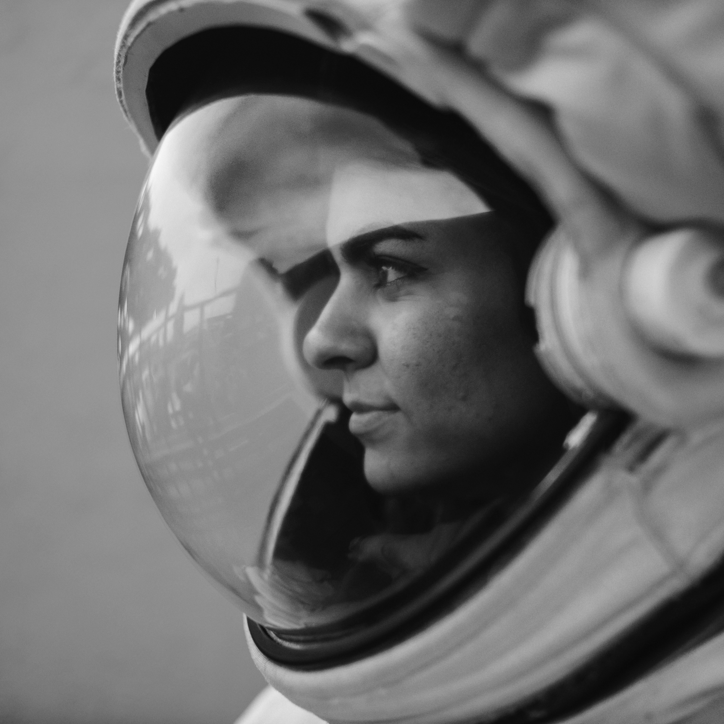 Close-up side profile of a woman wearing a helmet with a reflective visor, looking into the distance.