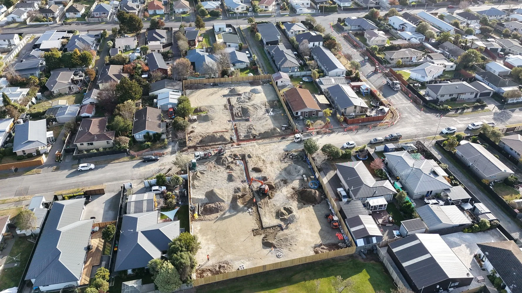 Aerial view of a residential neighborhood with a construction site and excavators in the process of digging.