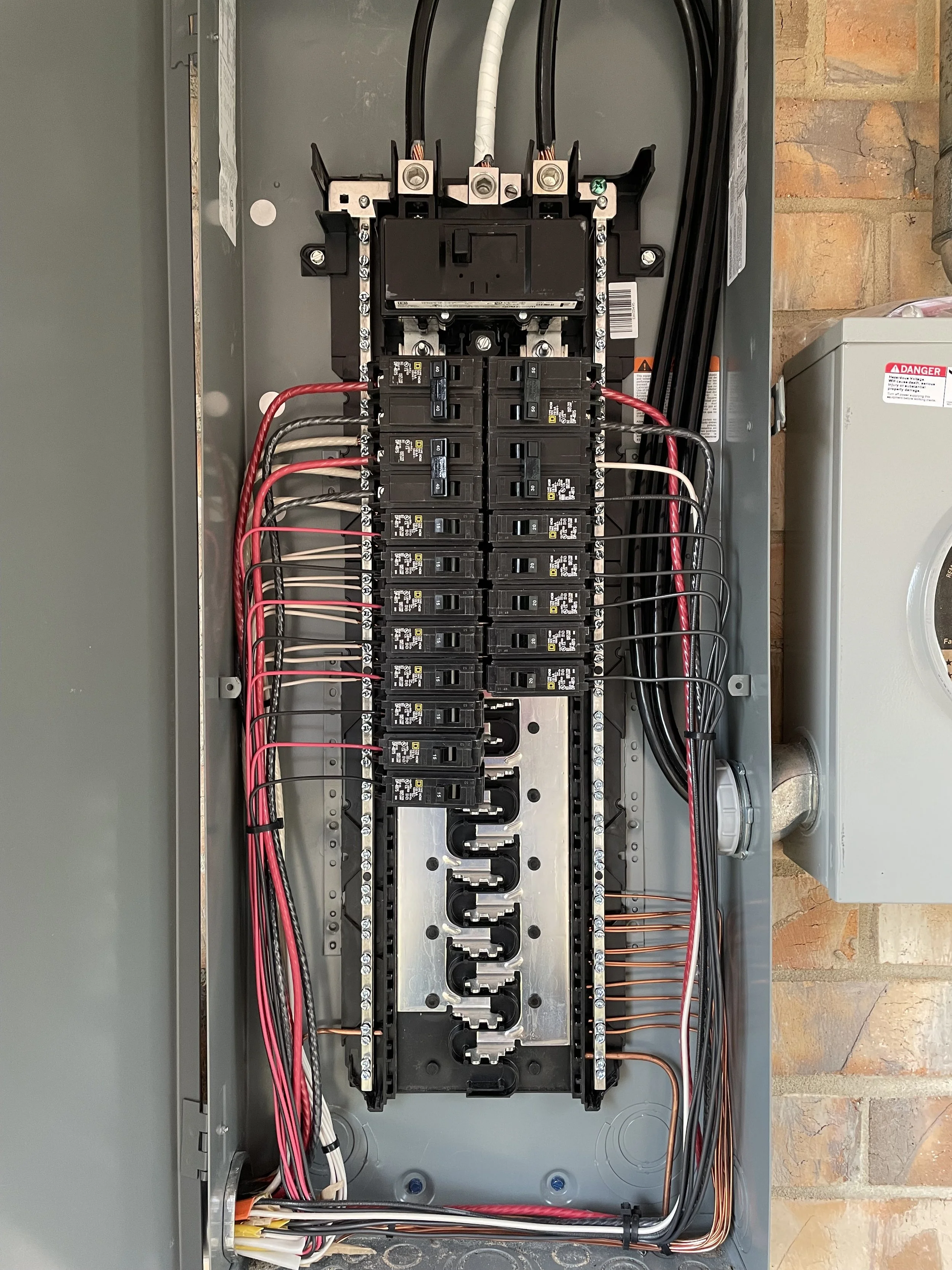 The image shows the inside of an electrical breaker panel with multiple circuit breakers and wiring organized along the sides and top of the panel.