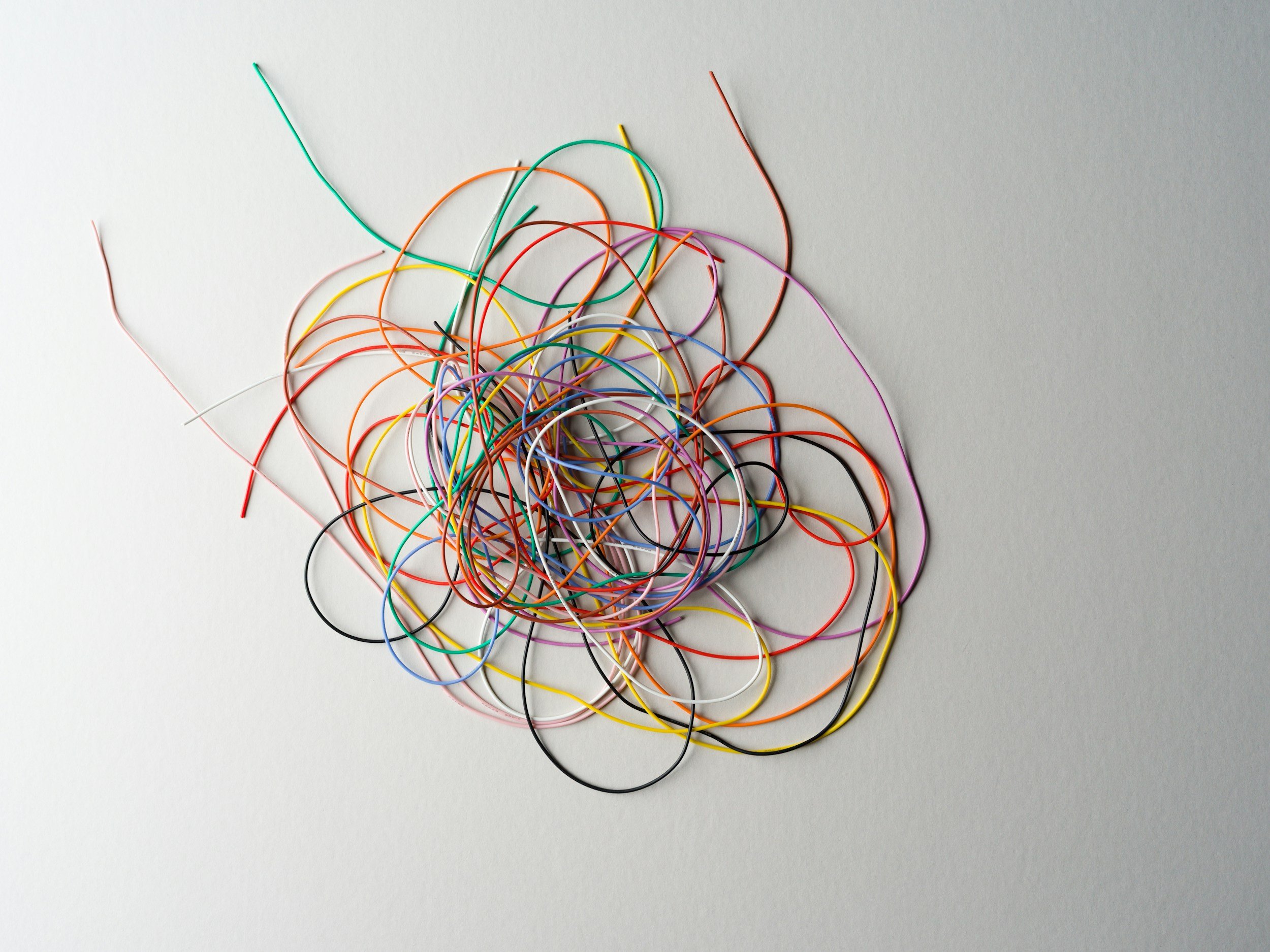 A pile of colorful rubber bands scattered on a white surface.