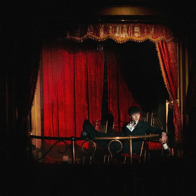 Portada de Betty Boop: artista sentado en un palco de teatro con cortinas rojas