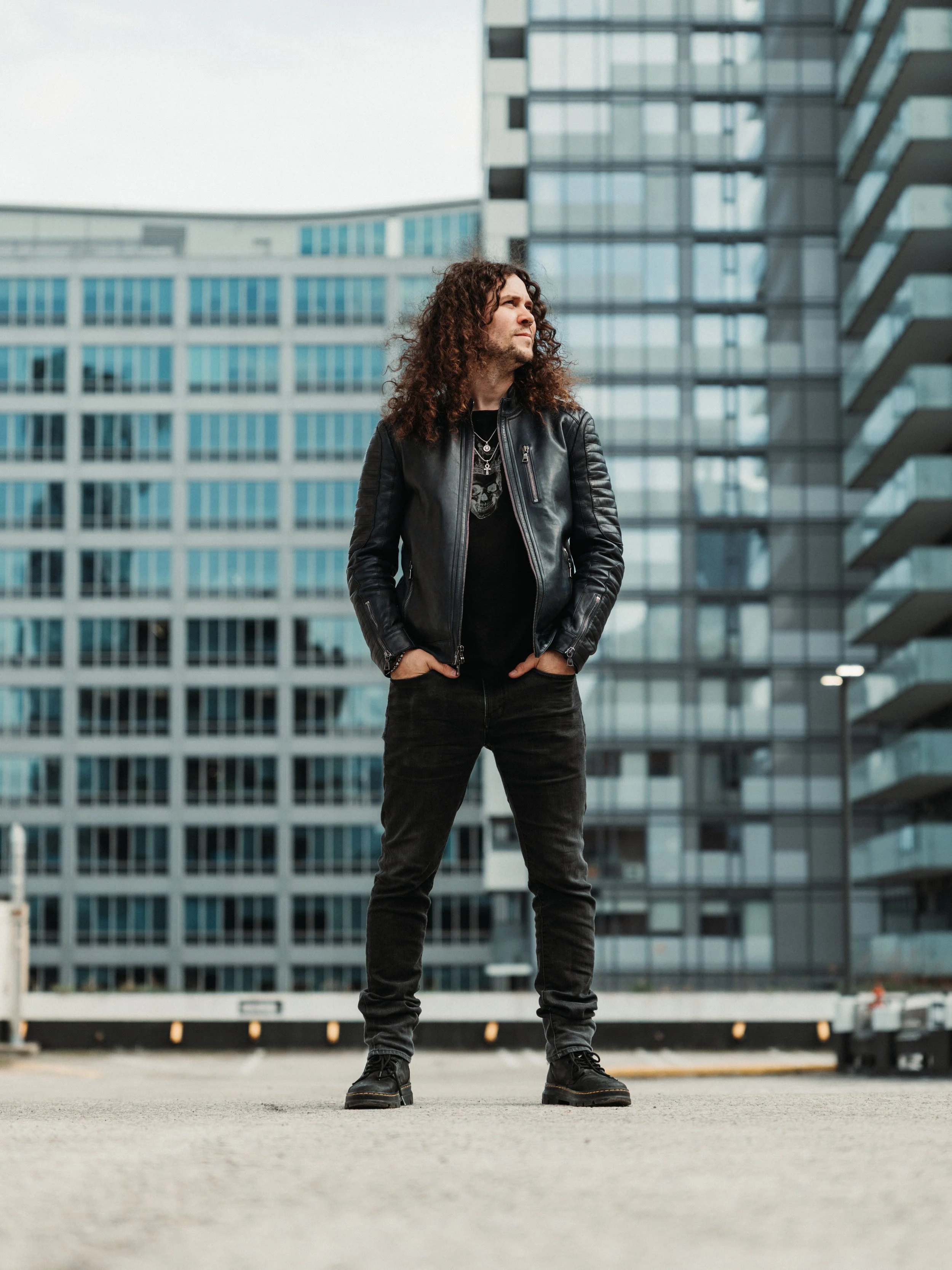 A photo of Kris Lamb standing with his hands in his pocket posing for a photo. He is look off to his left shoulder into the distance.