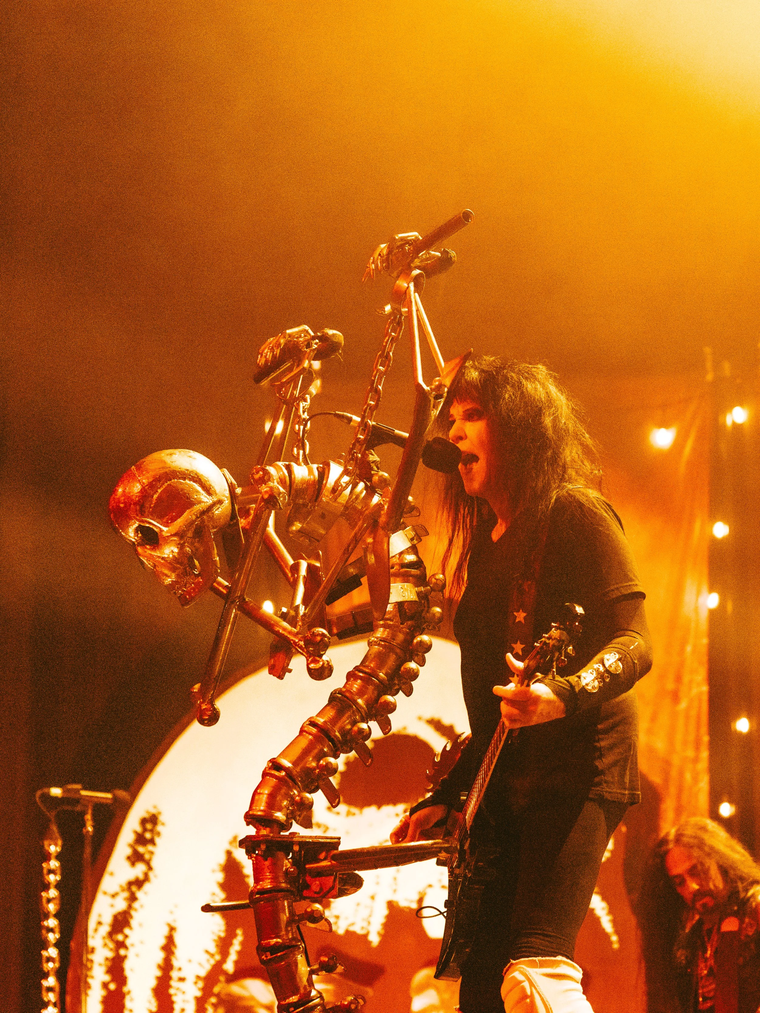 Blackie Lawless of W.A.S.P. signing and playing guitar on stage.