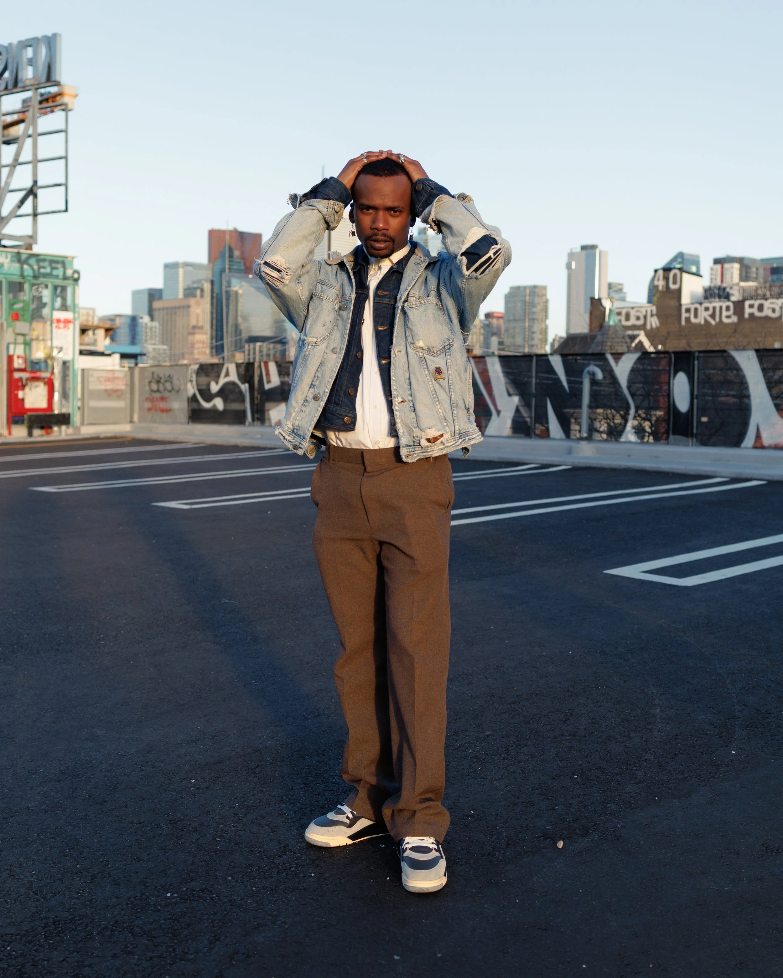 Chico holding his hands on the top of his head, posing with the Toronto skyline in the background.