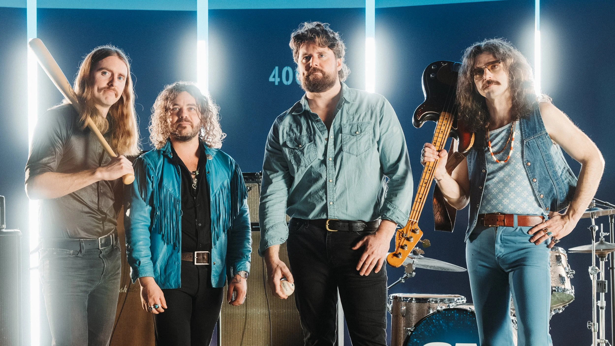 Ewan Currie, Ryan Gullen, Ricky Paquette and Shamus Currie of The Sheepdogs posing for a photo in a studio.