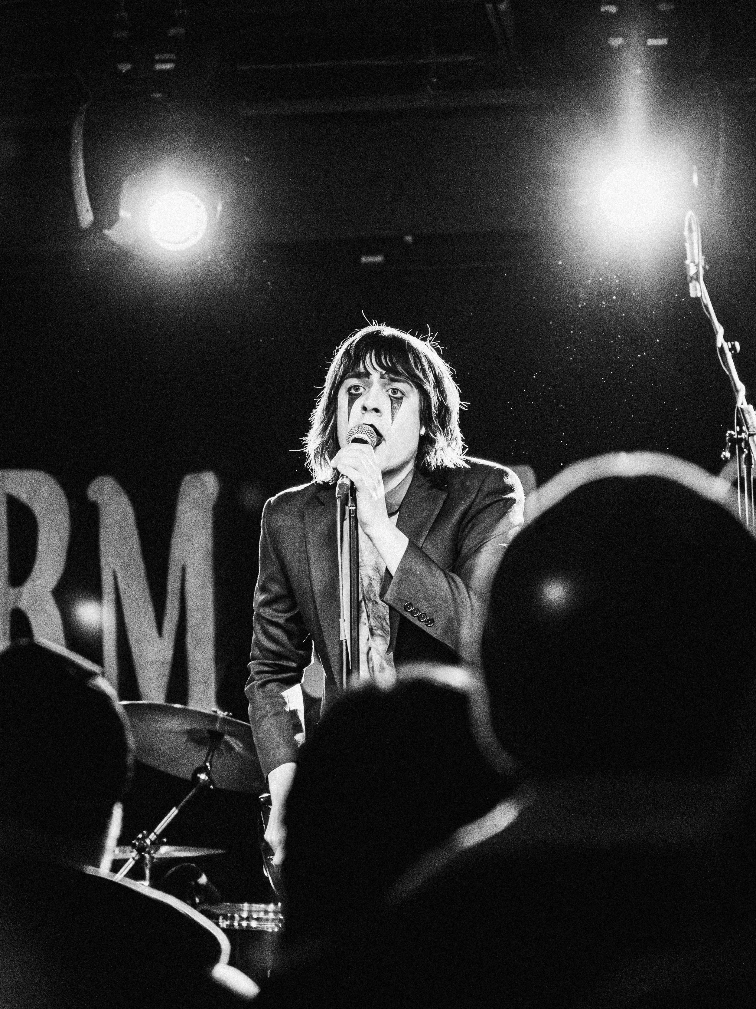 Rylan Whalen of Harm & Ease in clown make up signing into the mic.