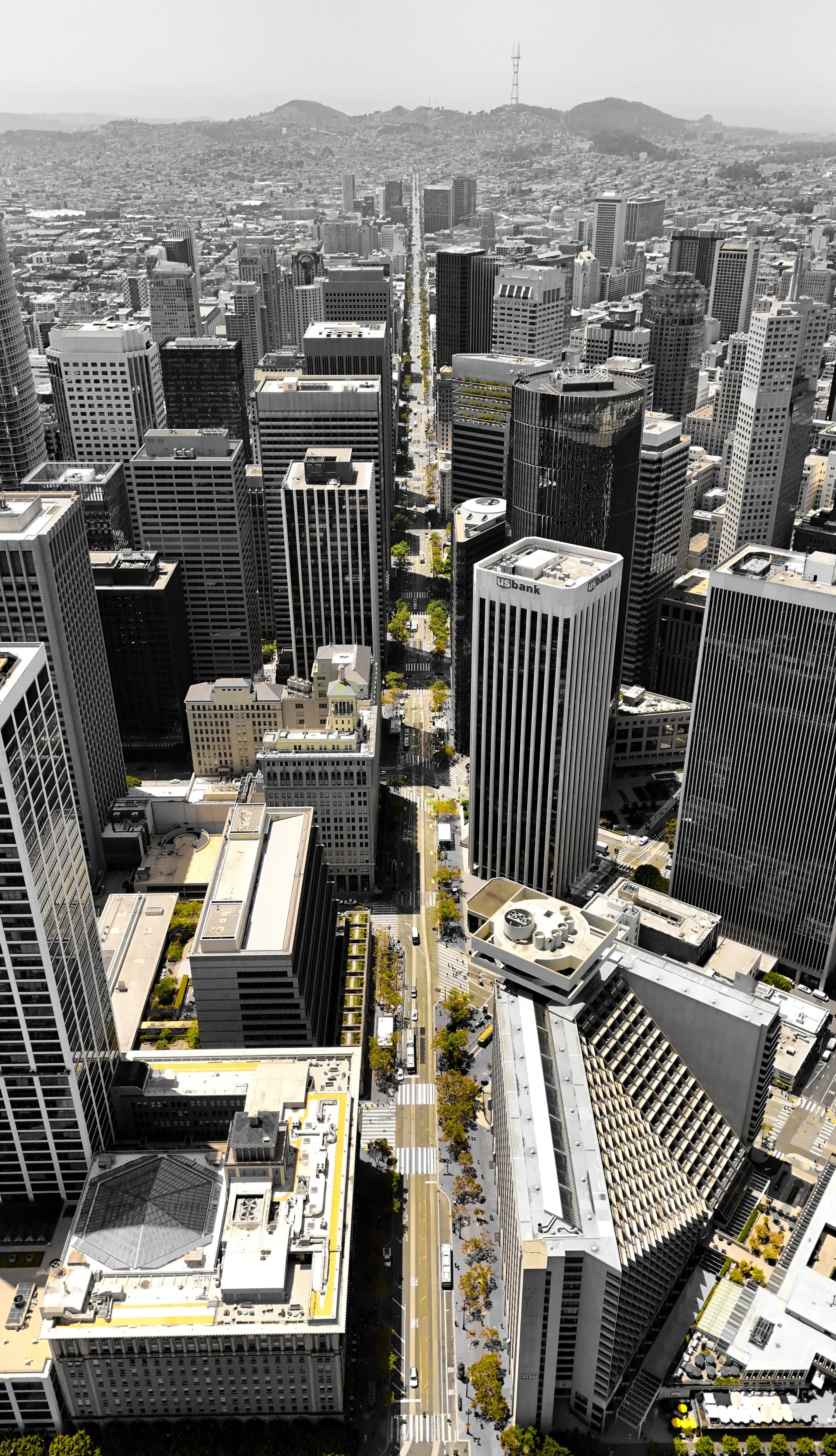 Aerial view of a city with tall skyscrapers, streets, and some greenery, taken on a clear day in daytime.