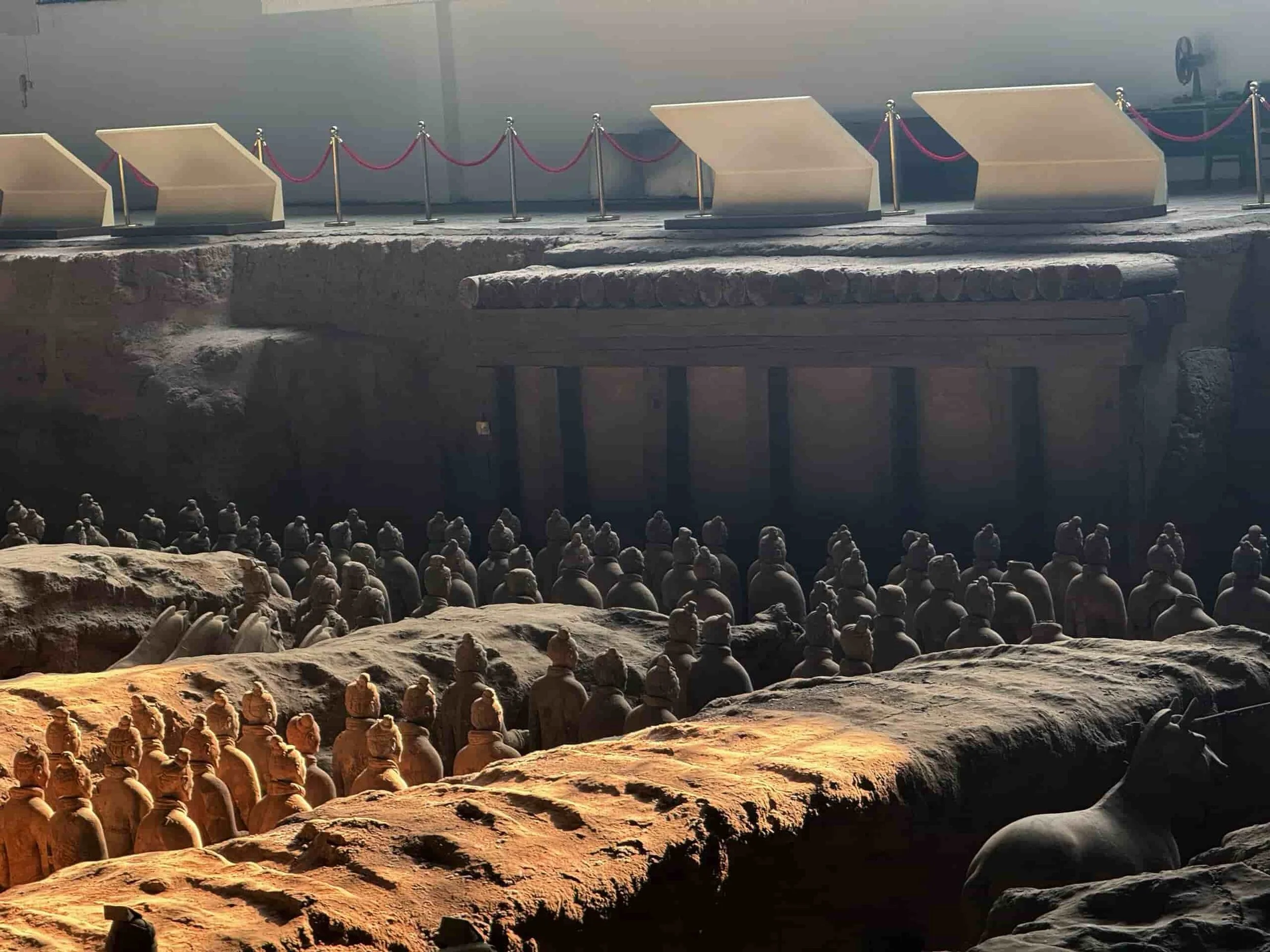 Terracotta warriors standing in rows inside an underground chamber with a dark background.