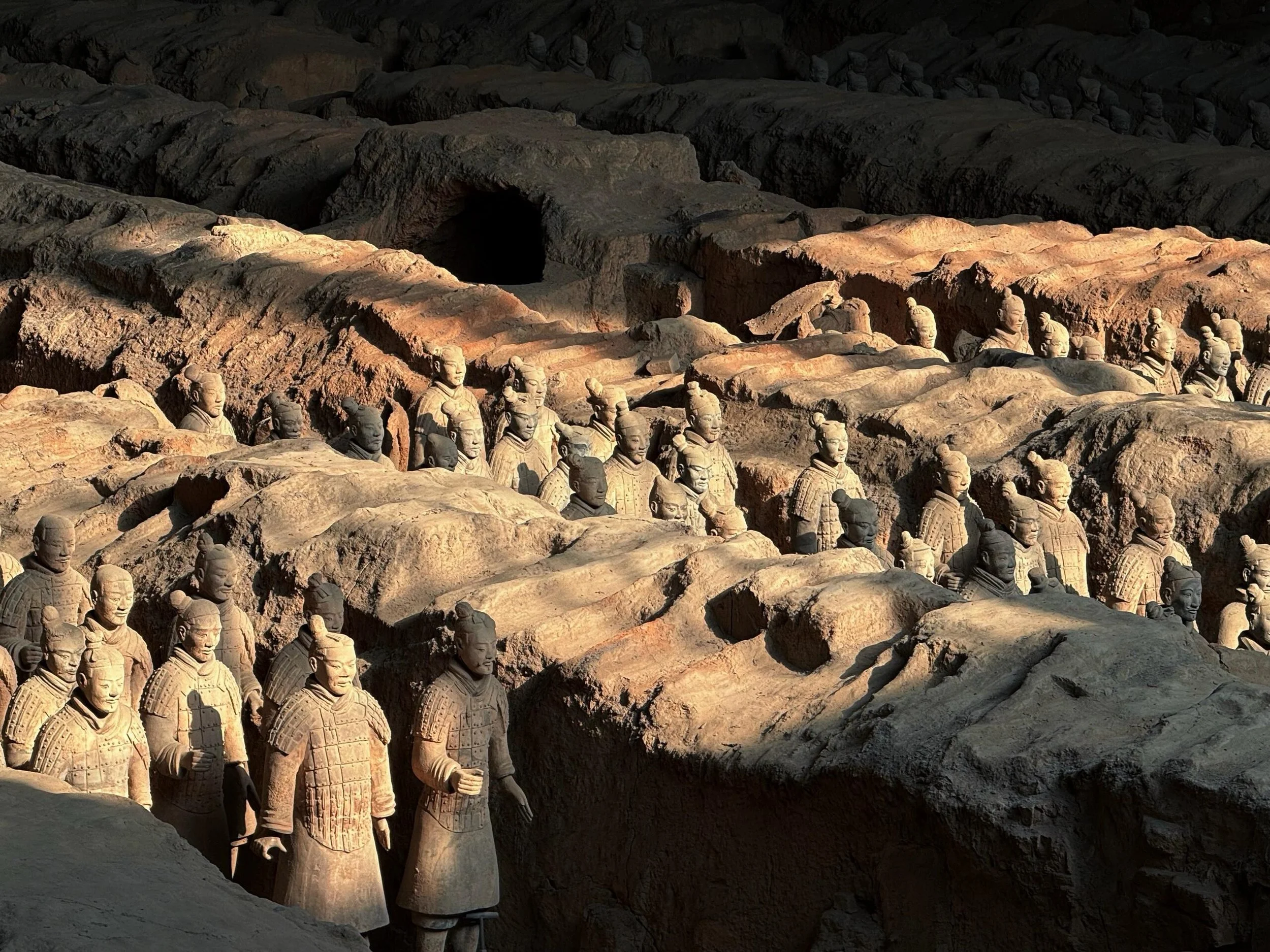 Terracotta warriors standing in rows inside an underground chamber with a dark background.
