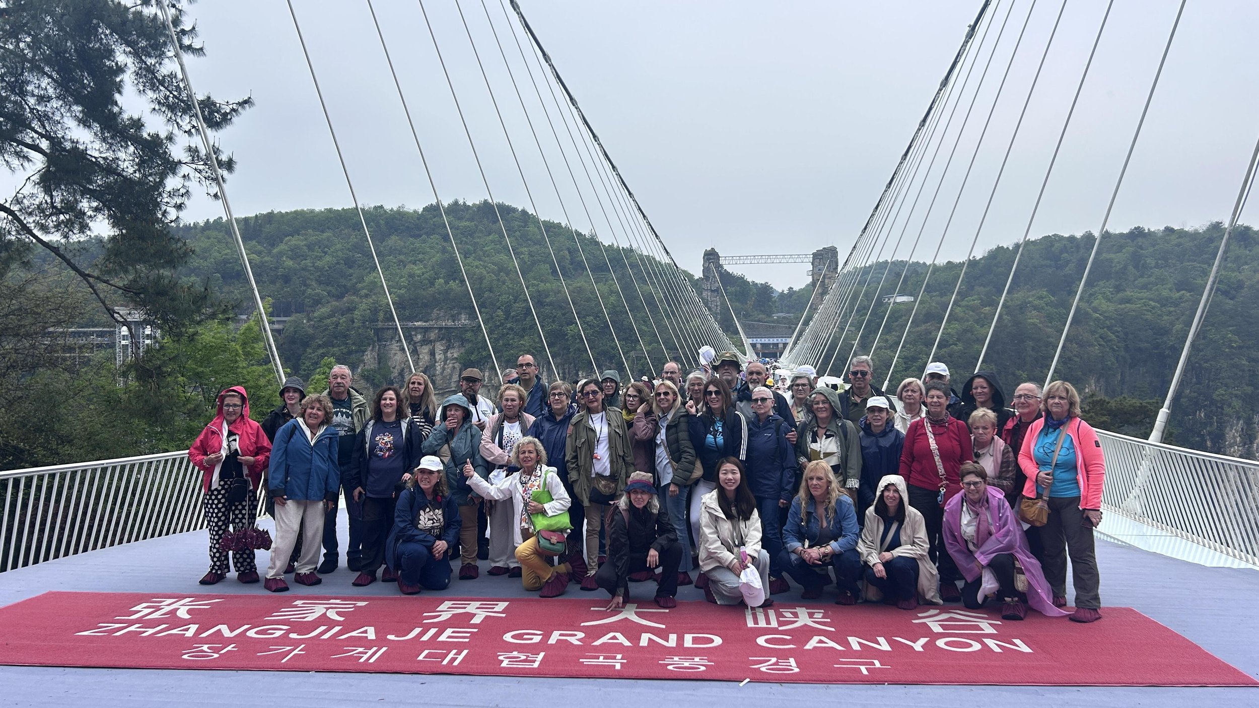 A large group of international travelers on the Zhangjiajie Grand Canyon Glass Bridge during a private China tour
