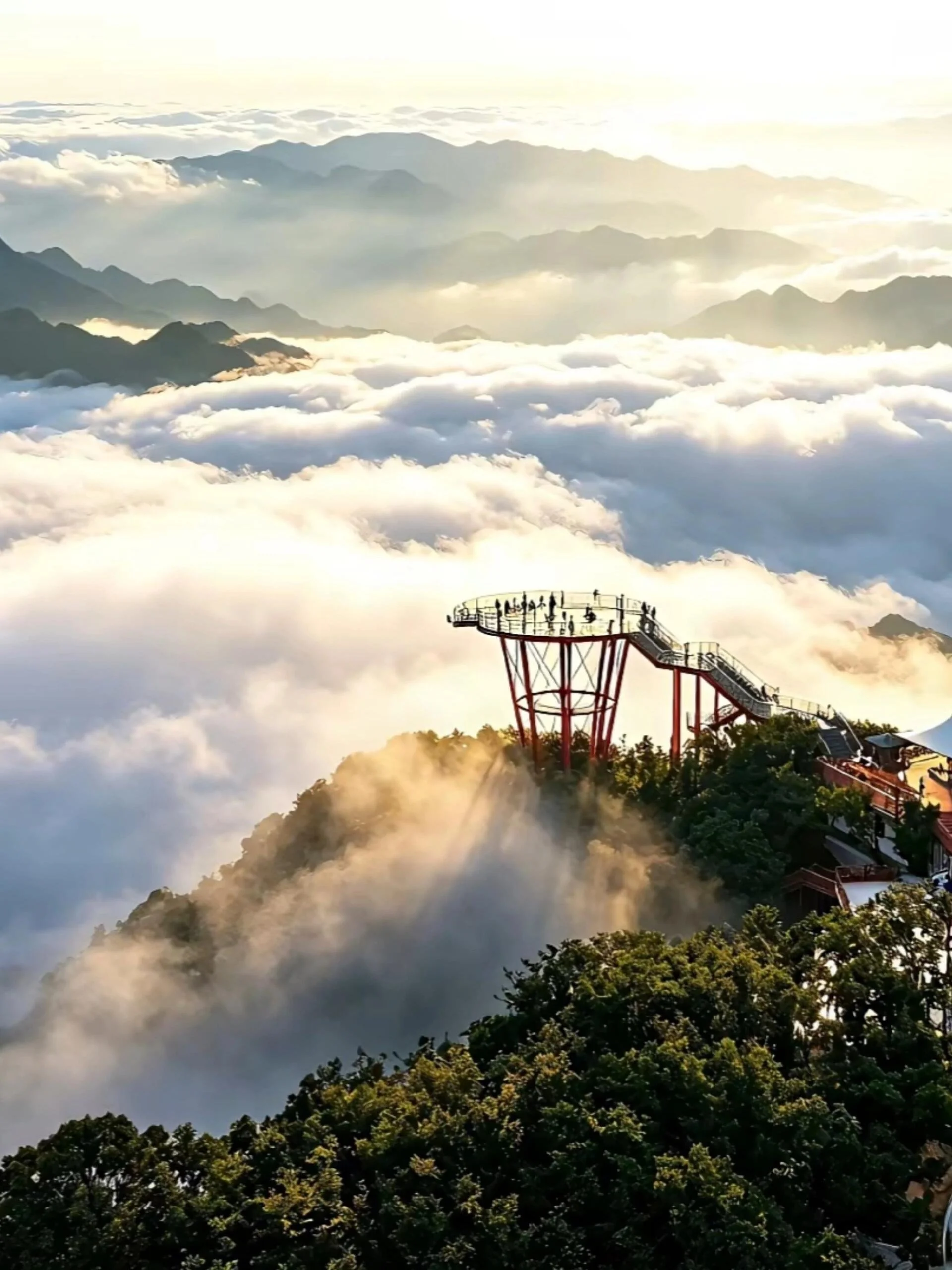 The red 1520 Sky Eye observation platform at Qixing Mountain Zhangjiajie standing above a vast golden sea of clouds with visitors on the deck and layered mountain ridgelines in the distance at sunset