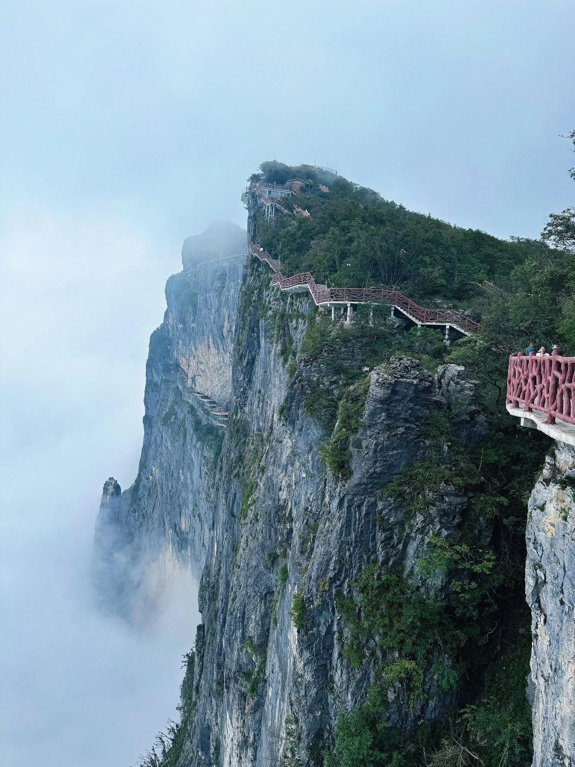 Thick clouds and mist rolling over the rocky cliffs and red-railed plank walkway near Star-Picking Platform (Zhixingtai) on Qixing Mountain Zhangjiajie