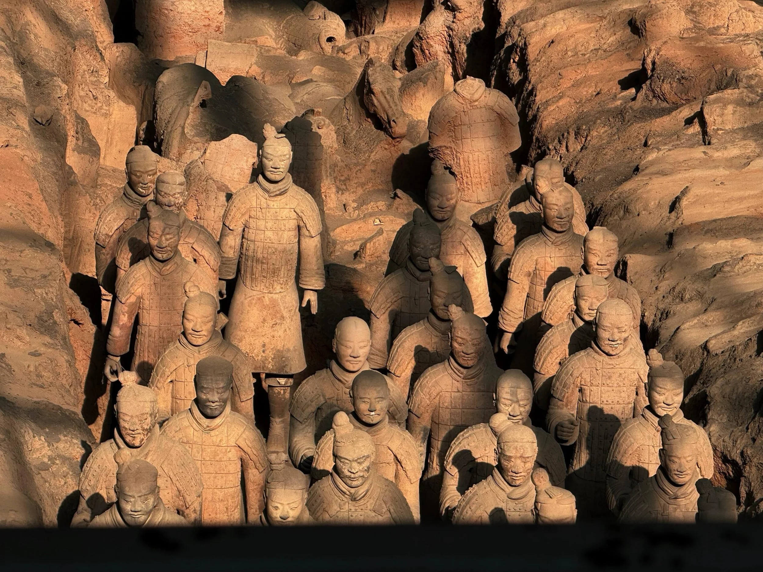 Terracotta warriors statues in a formation, featuring detailed armor and facial expressions, part of an ancient Chinese archaeological site.